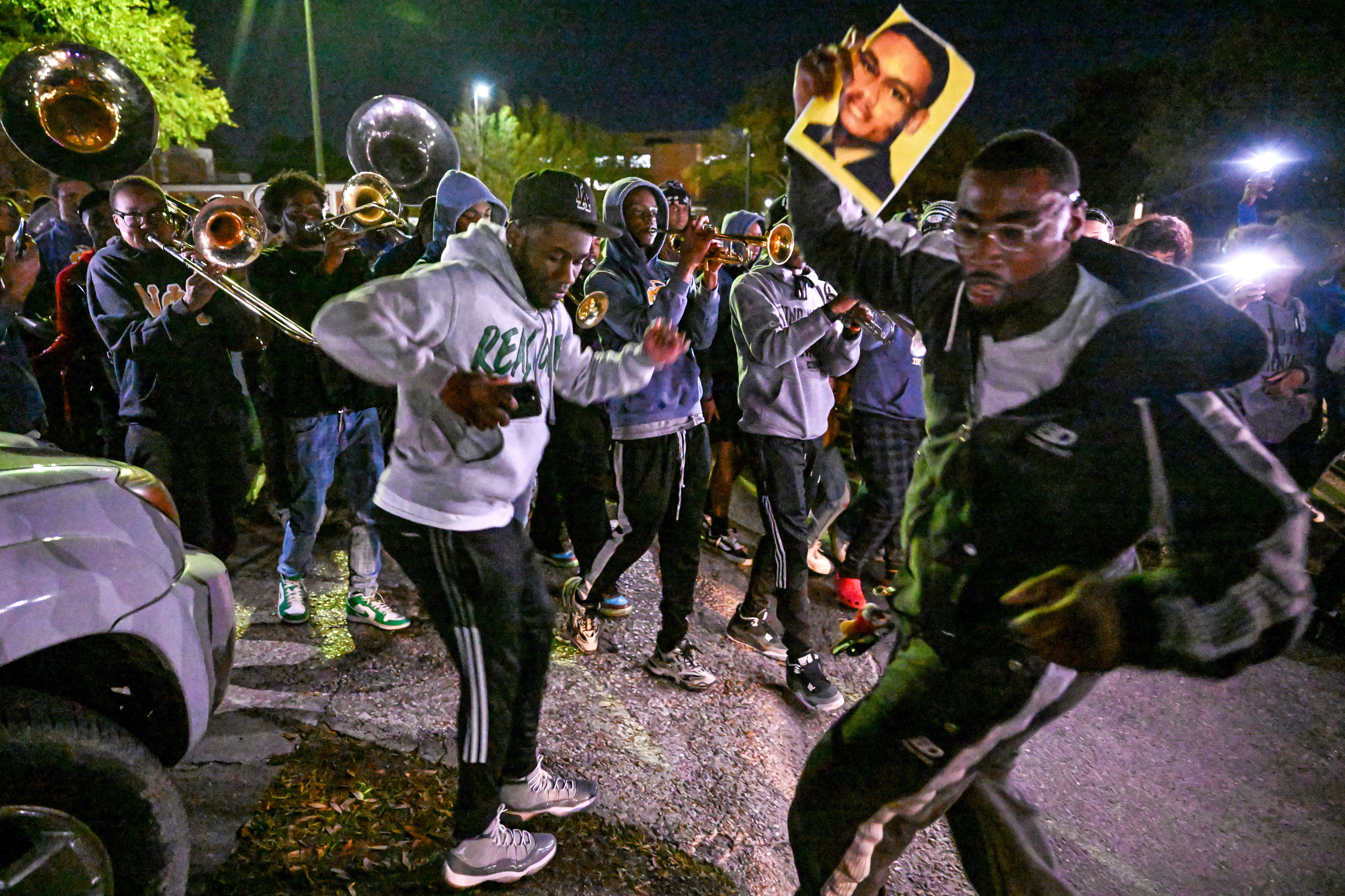 Mourners dance while holding up pictures of Caleb Wilson during a vigil