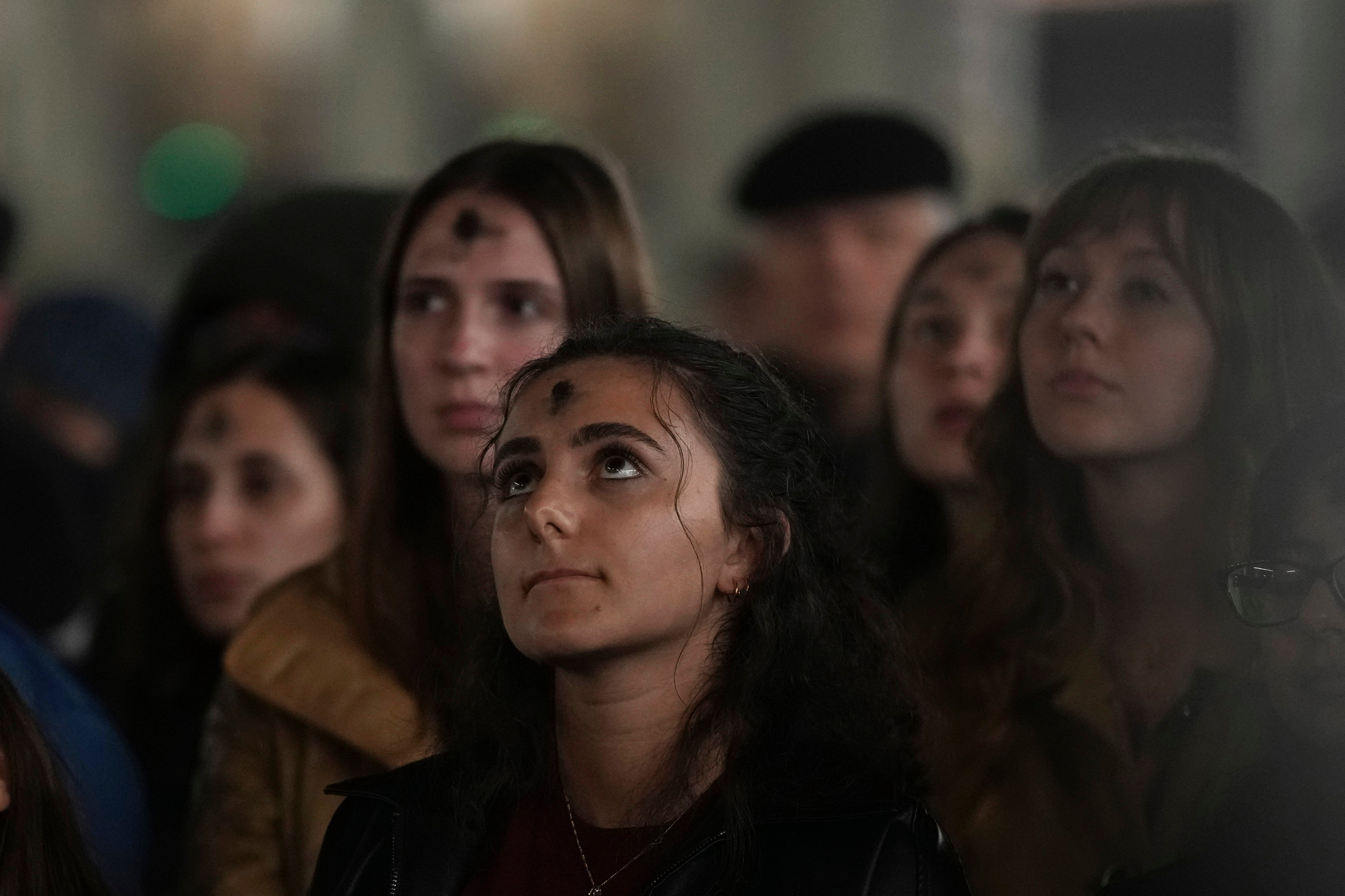 People, with ashes on their foreheads, pray in St Peter’s Square