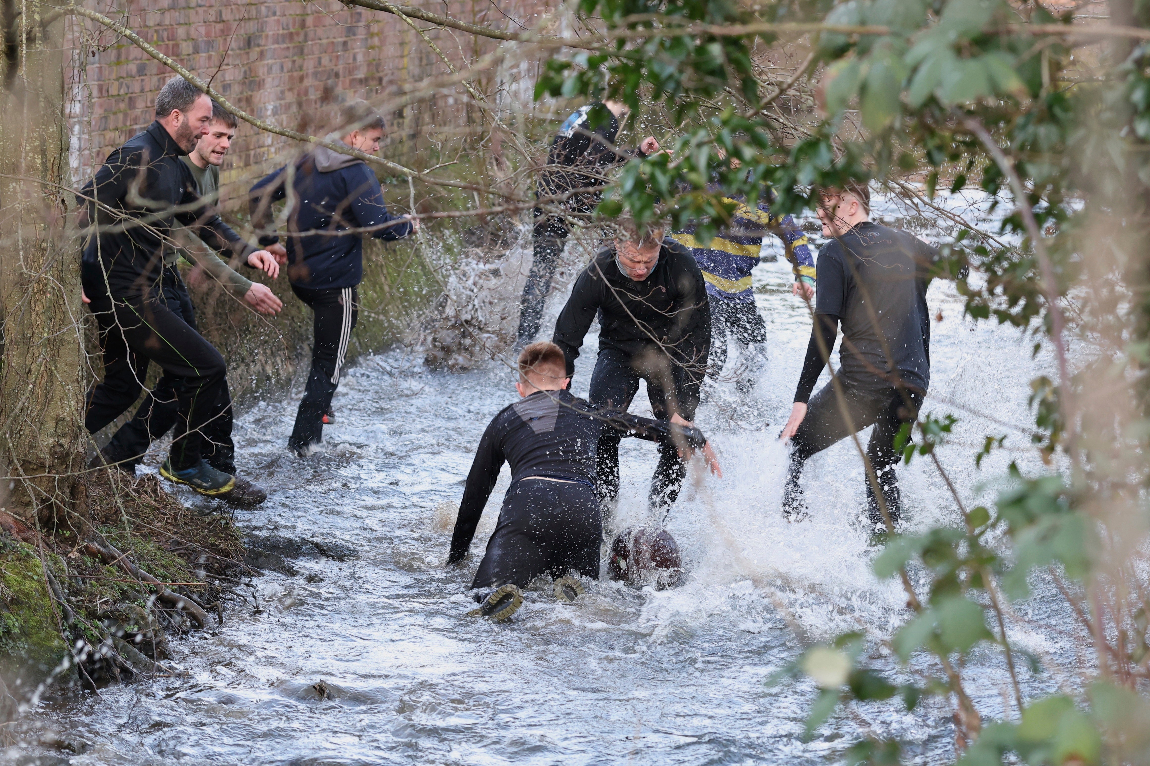 Players try to grab the ball from the Henmore Brook during the annual Shrovetide medieval match in Ashbourne