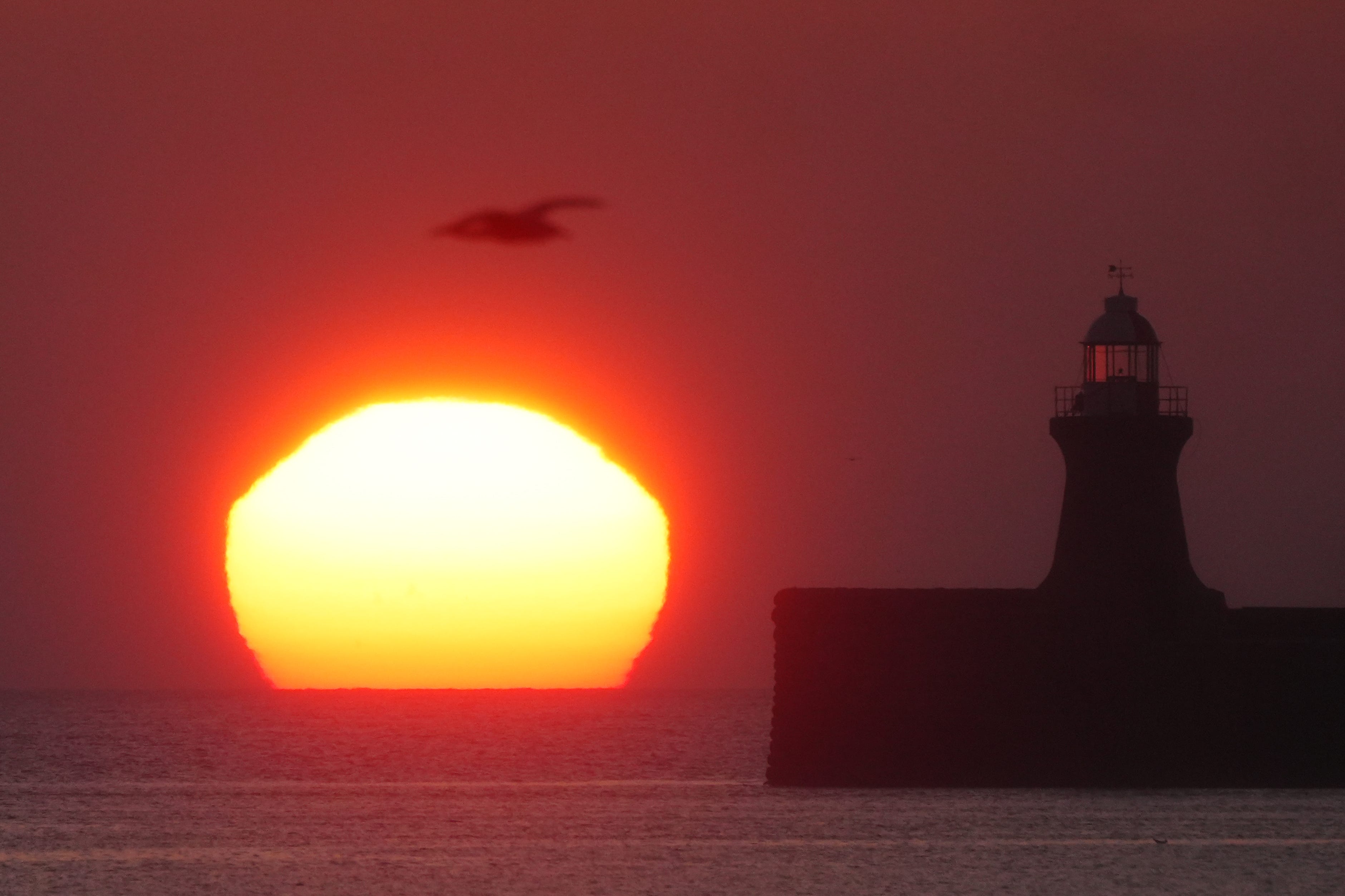 The sun begins to rise behind South Shields lighthouse (Owen Humphreys/PA)