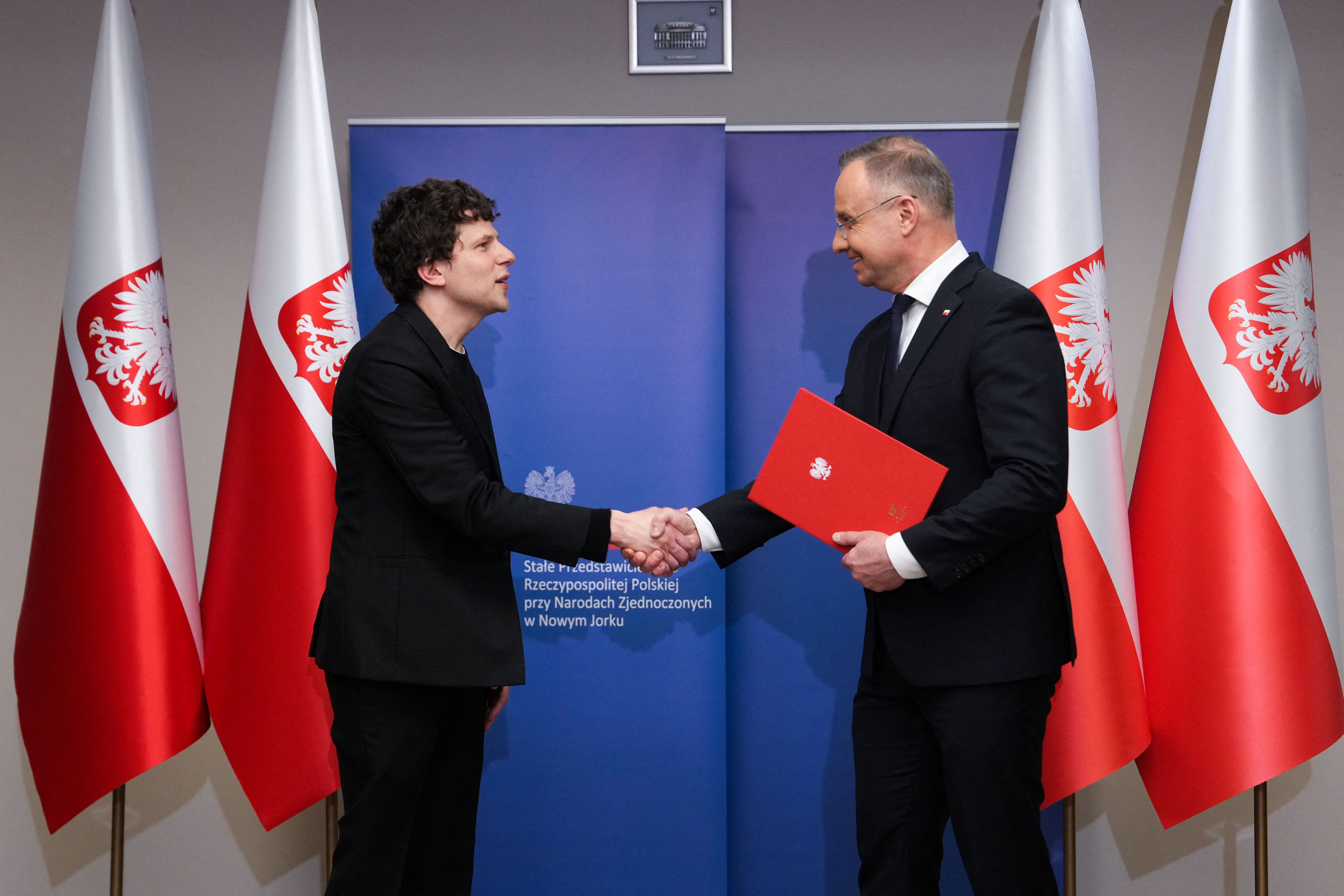 Polish President Andrzej Duda shakes hands with Jesse Eisenberg as he grants him Polish citizenship