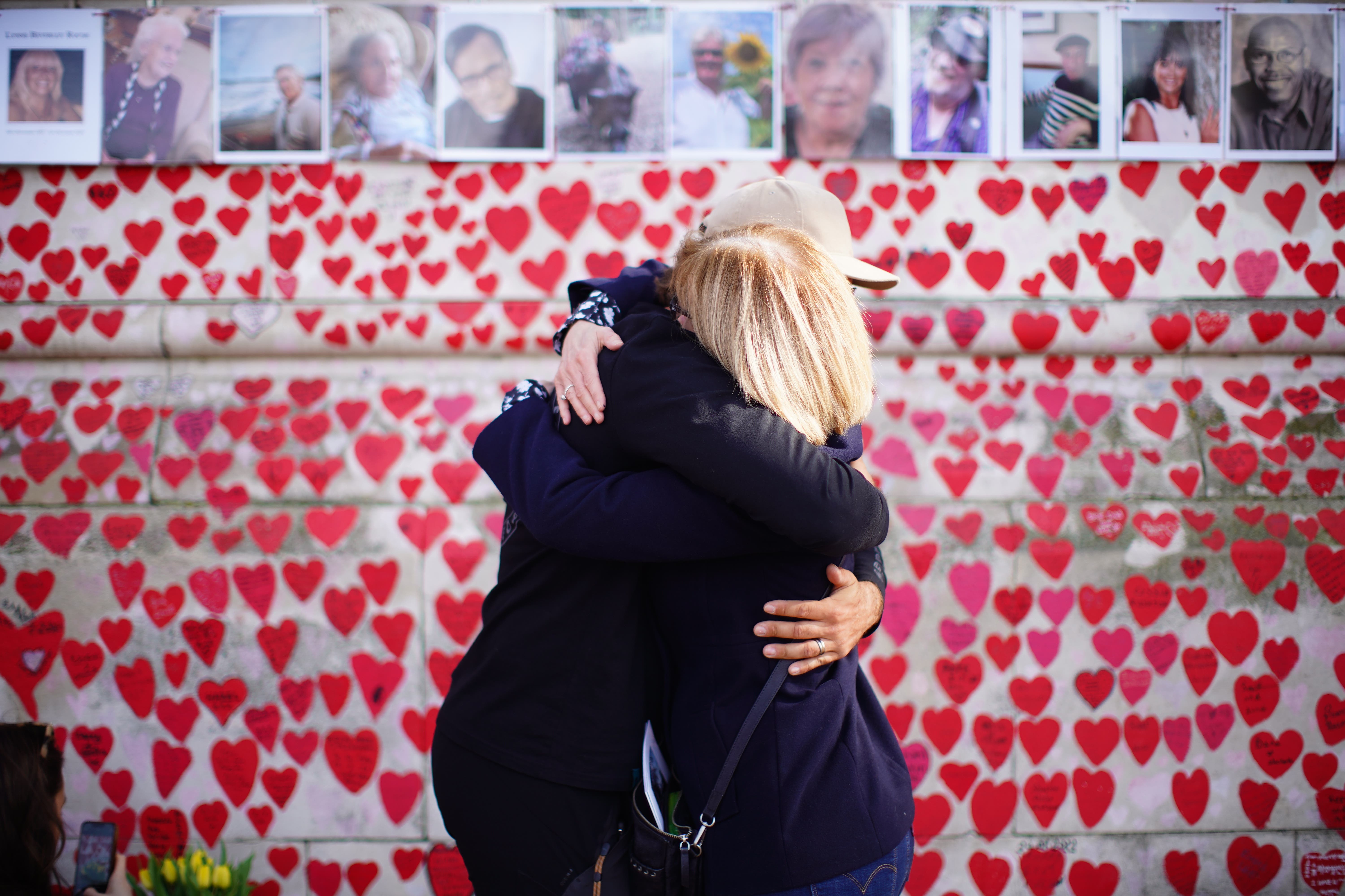 People hugging as they attend a ceremony marking the fifth anniversary of the Covid-19 pandemic at the National Covid Memorial Wall in London (James Manning/PA)