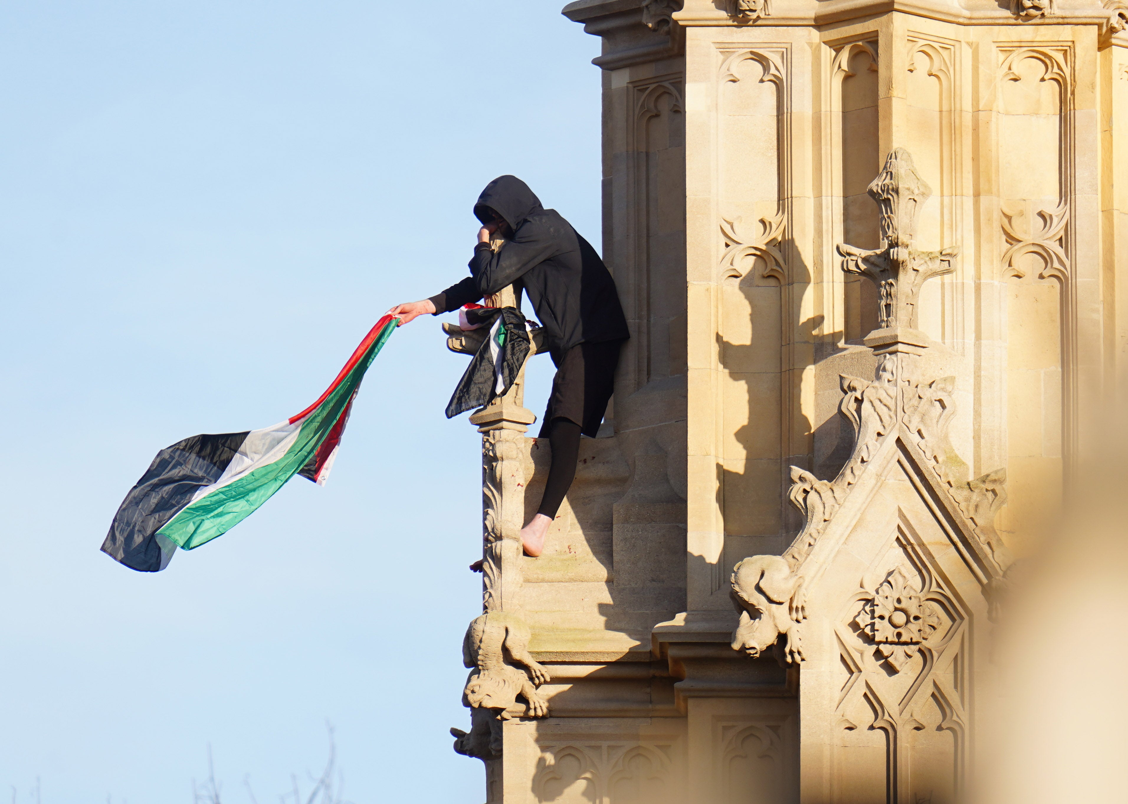 The man waves a Palestinian flag from his vantage point on the Elizabeth Tower