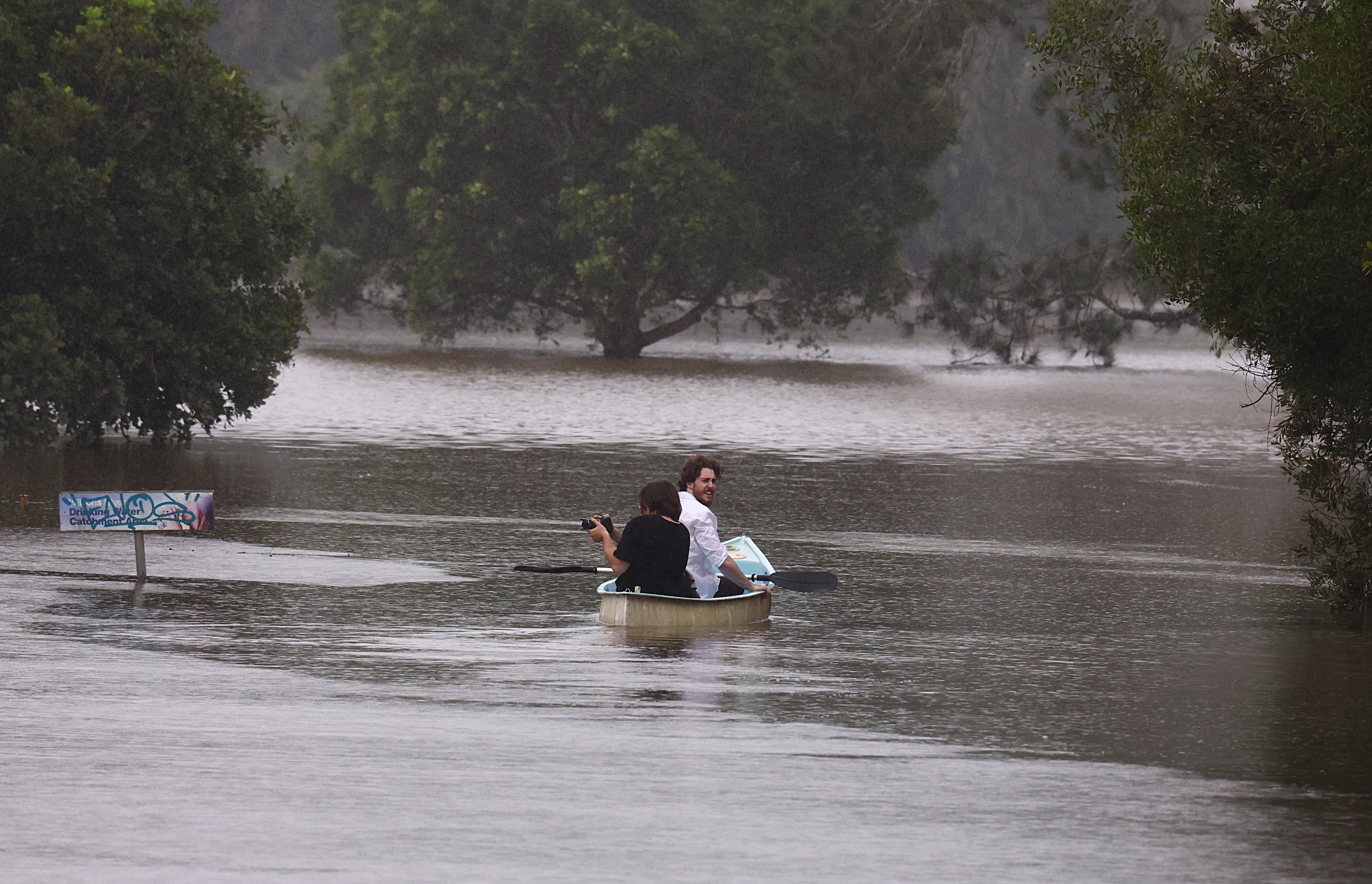 People paddle a canoe down a street in South Lismore, New South Wales, on 10 March 2025