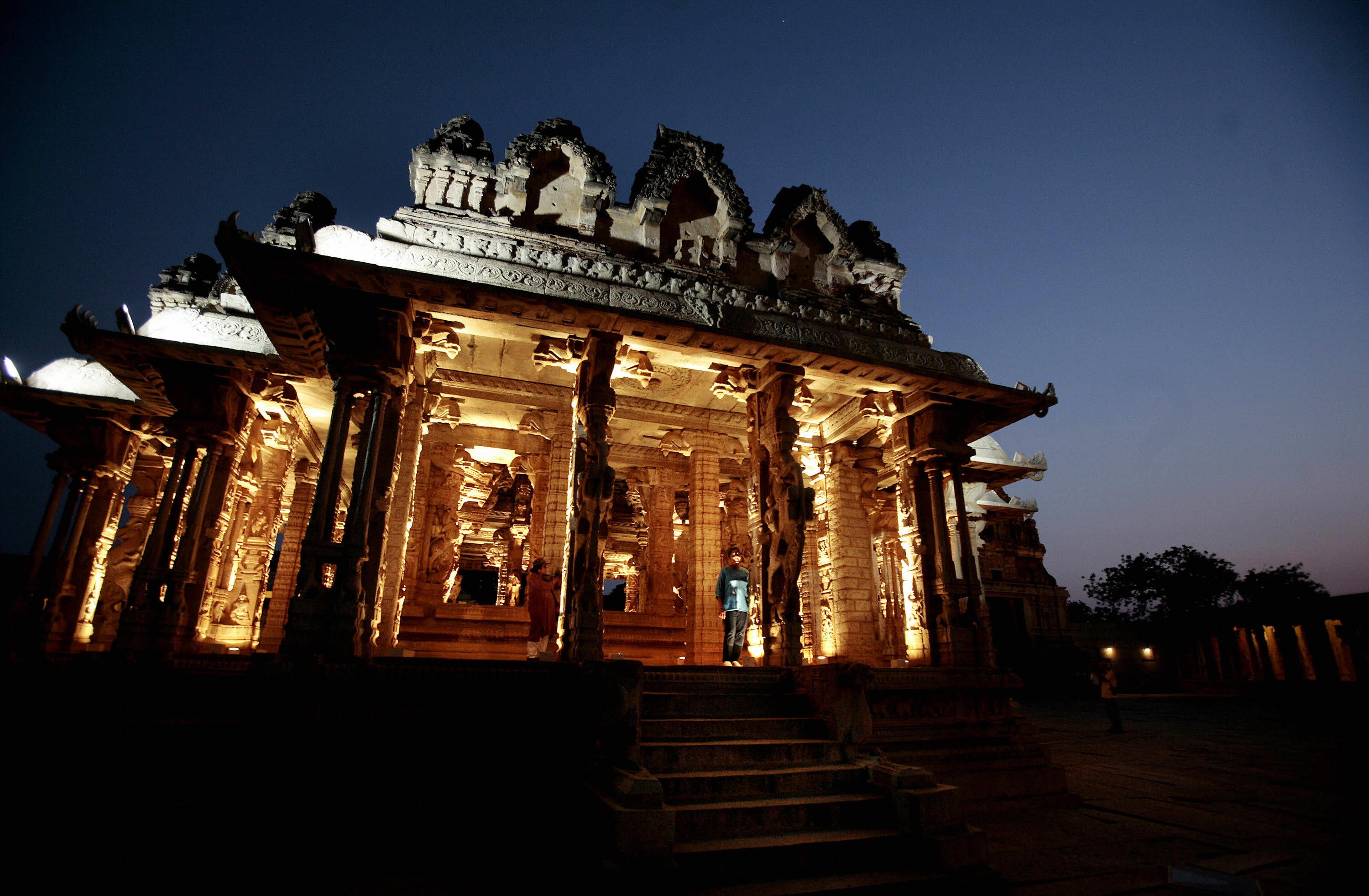 File: Tourists walk through a temple complex in Hampi