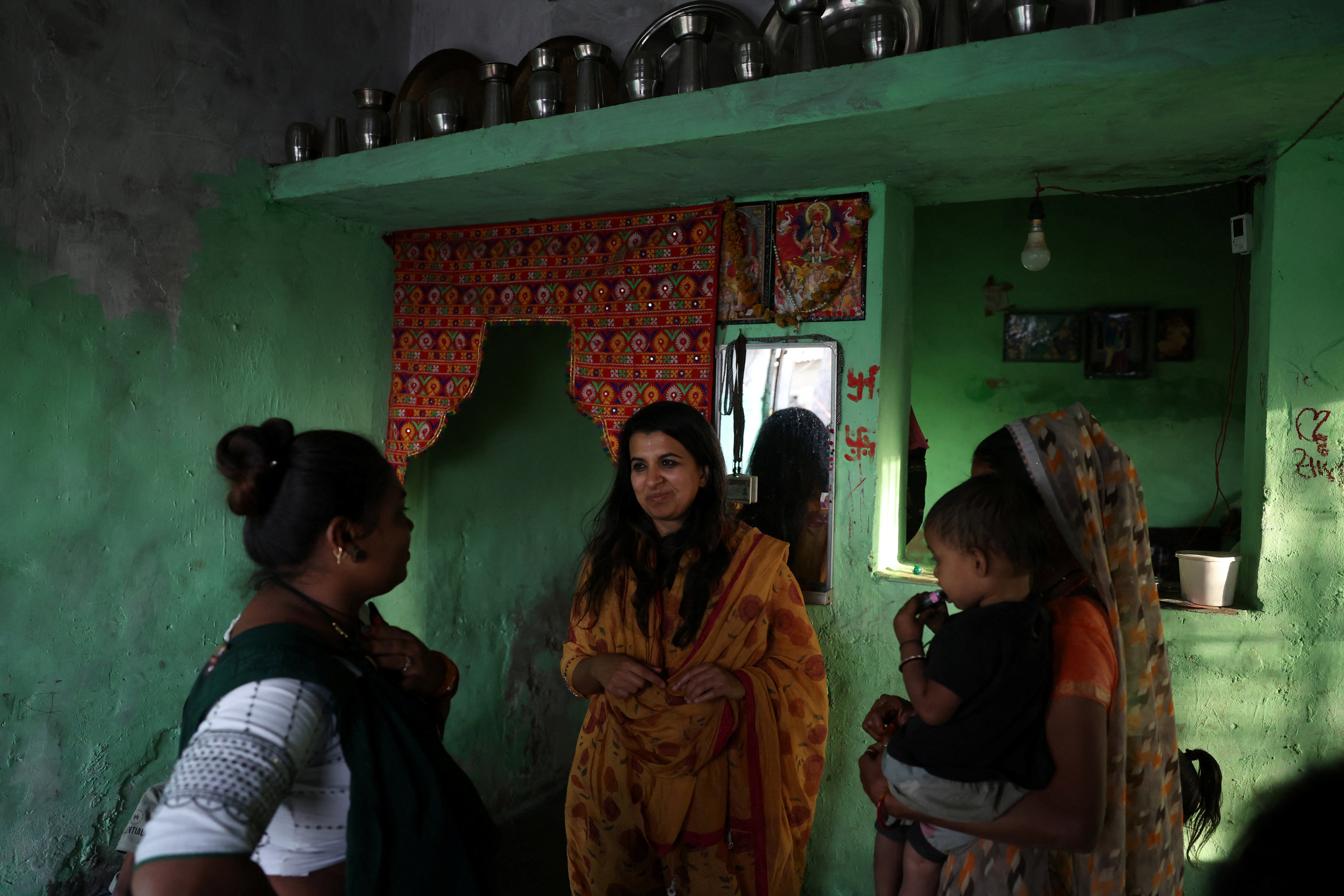 Aditi Bunker, an epidemiologist, speaks with Manisha Barot and Roshani Barot, whose one-room house's rooftop has been coated with liquid-applied membrane