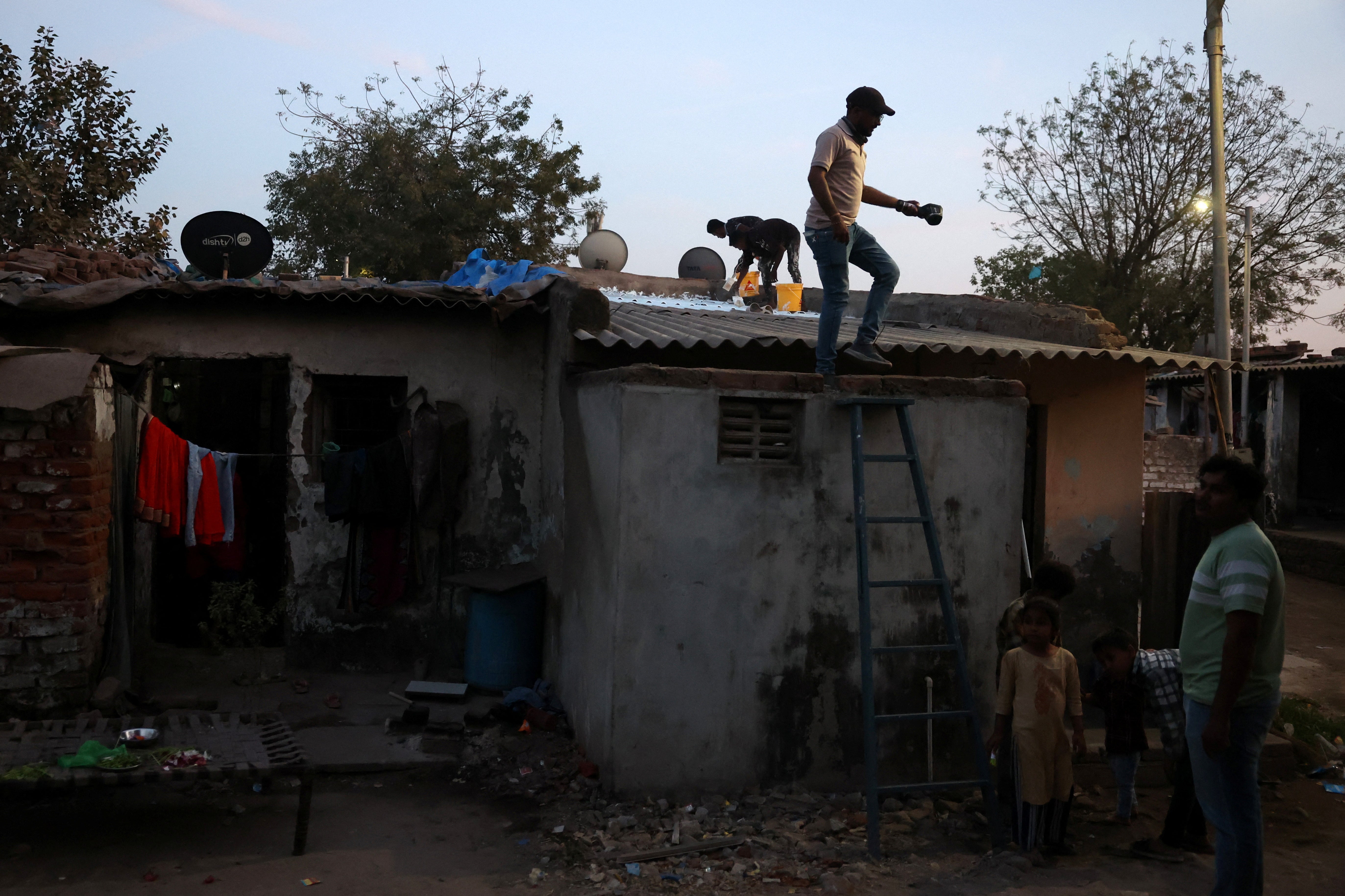 Ajit Thakor, a field supervisor, climbs down from a one-room house after measuring its temperature