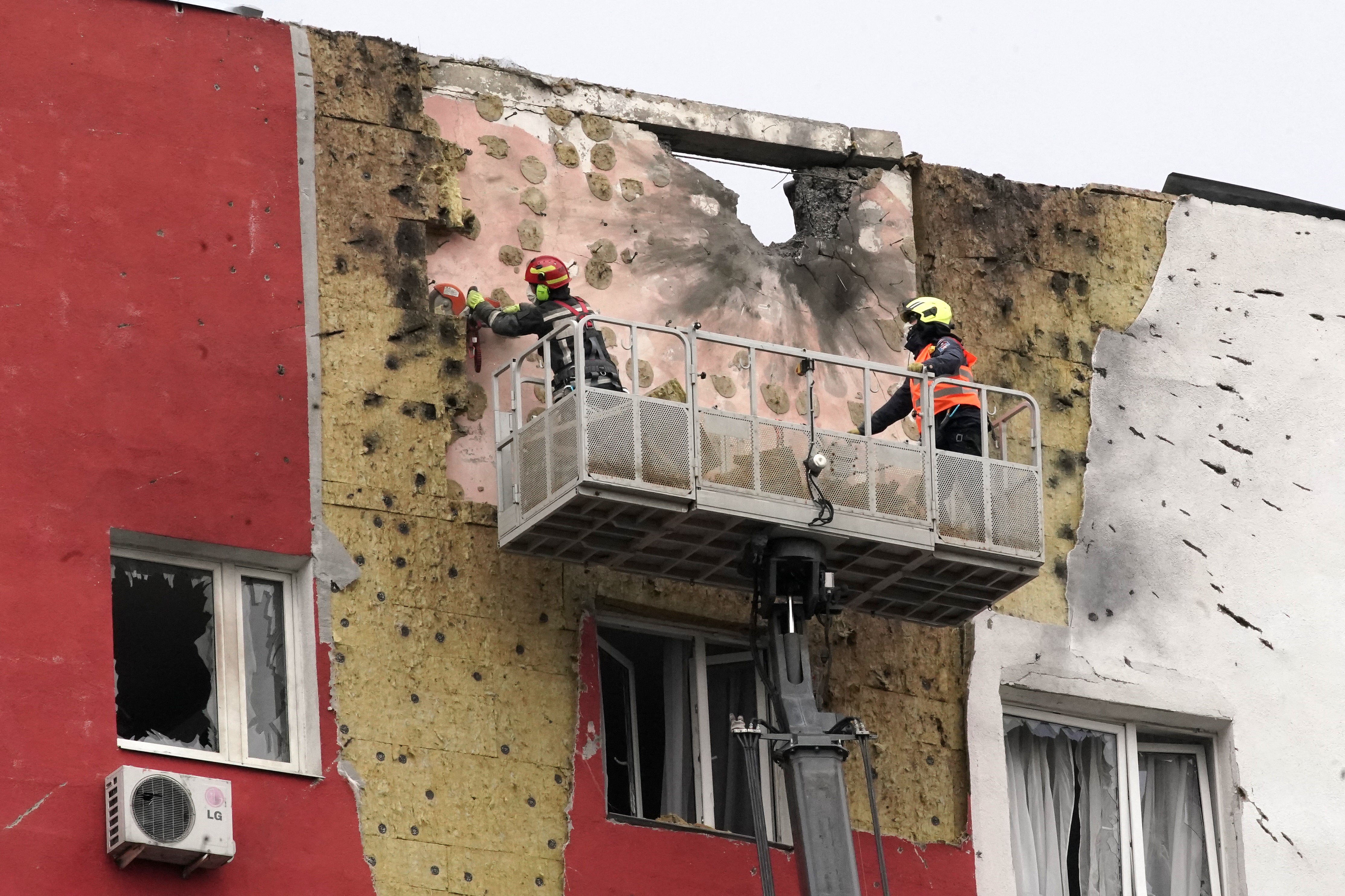Specialists work on the facade of a damaged apartment building following a drone attack in Moscow