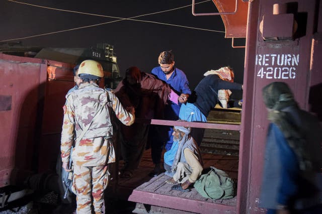 <p>Soldier helps evacuate freed train passengers at the Mach railway station in Pakistan</p>