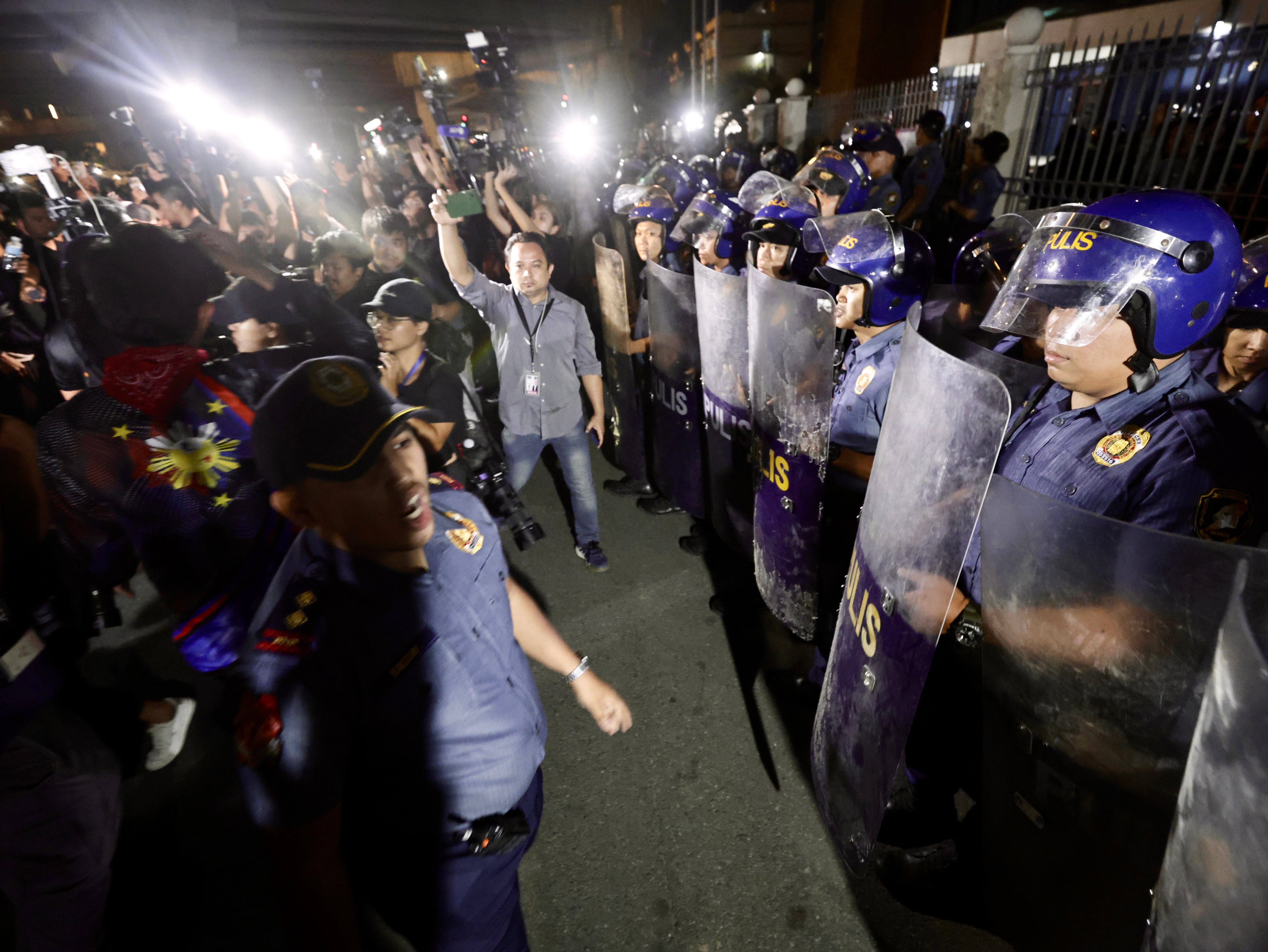 Police stand in formation at the gates of a military airbase where former president Rodrigo Duterte was held in Manila