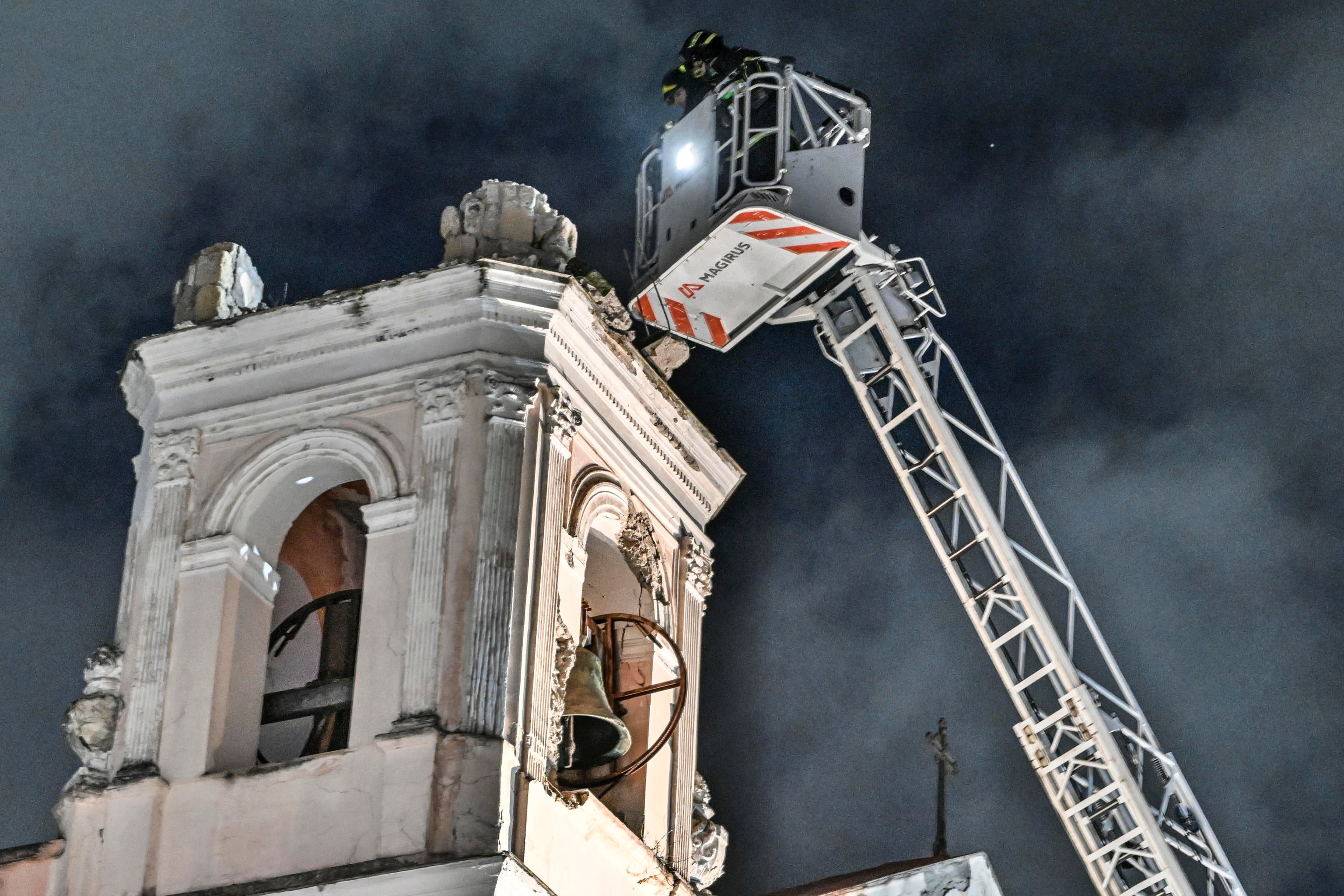 Firefighters inspect a bell tower at the church of Sant’Anna following an earthquake, in Bagnoli