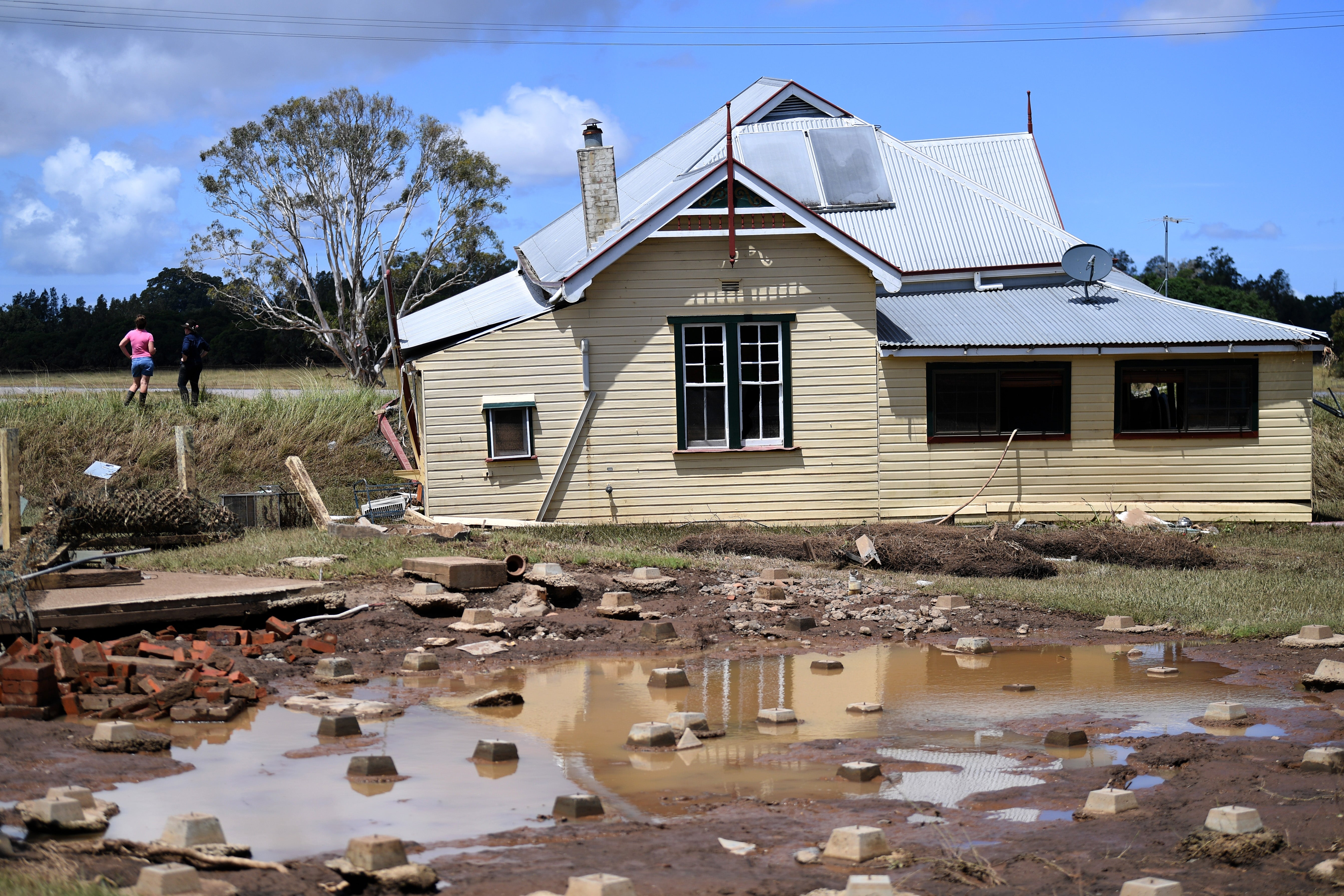 Resident inspects her destroyed house which was pushed off its foundation by floodwater on their rural property on near Wyrallah, Australia