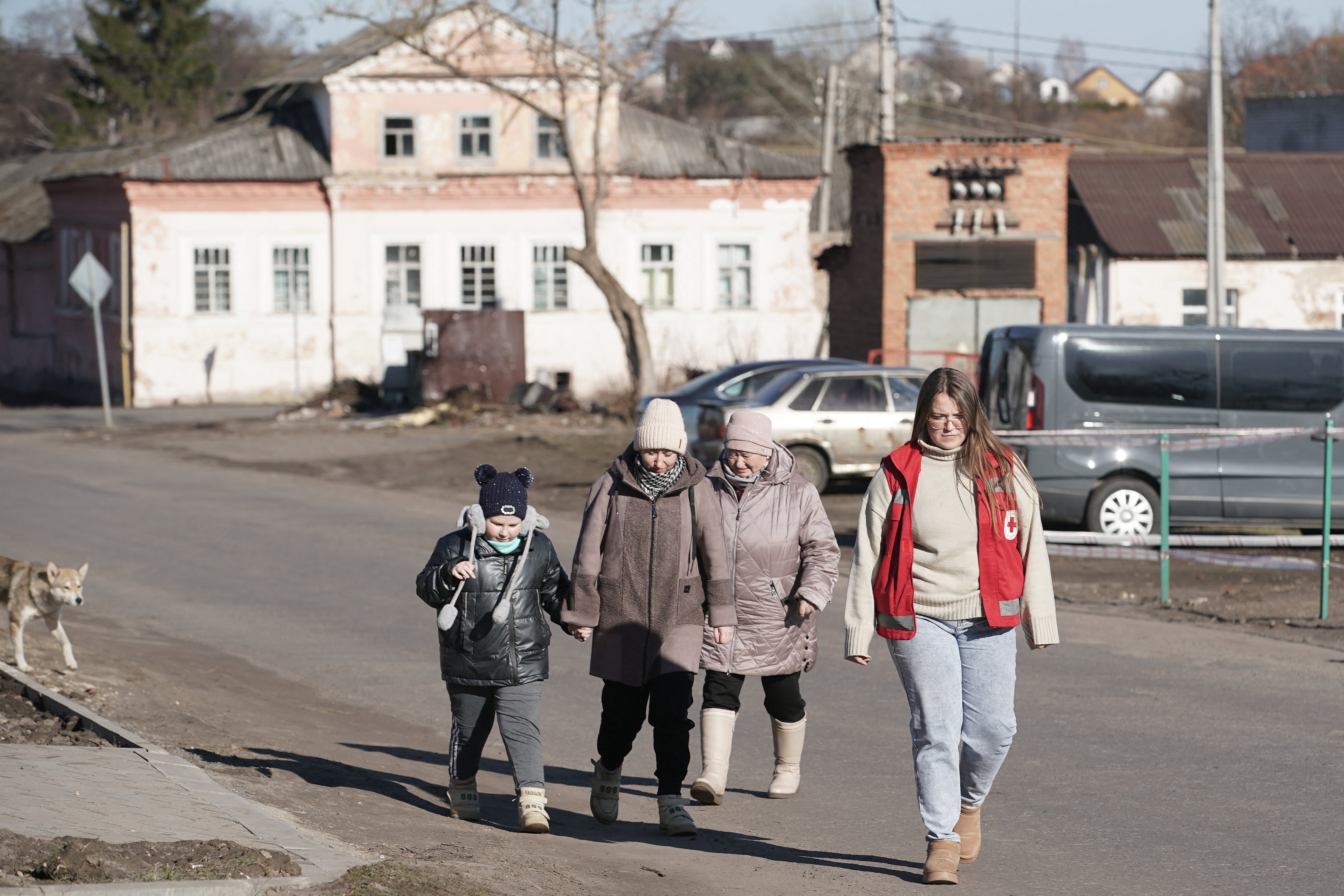 Evacuees from the village of Martynovka in Sudzha district, walk along the street in Fatezh, Kursk region, with a Red Cross volunteer