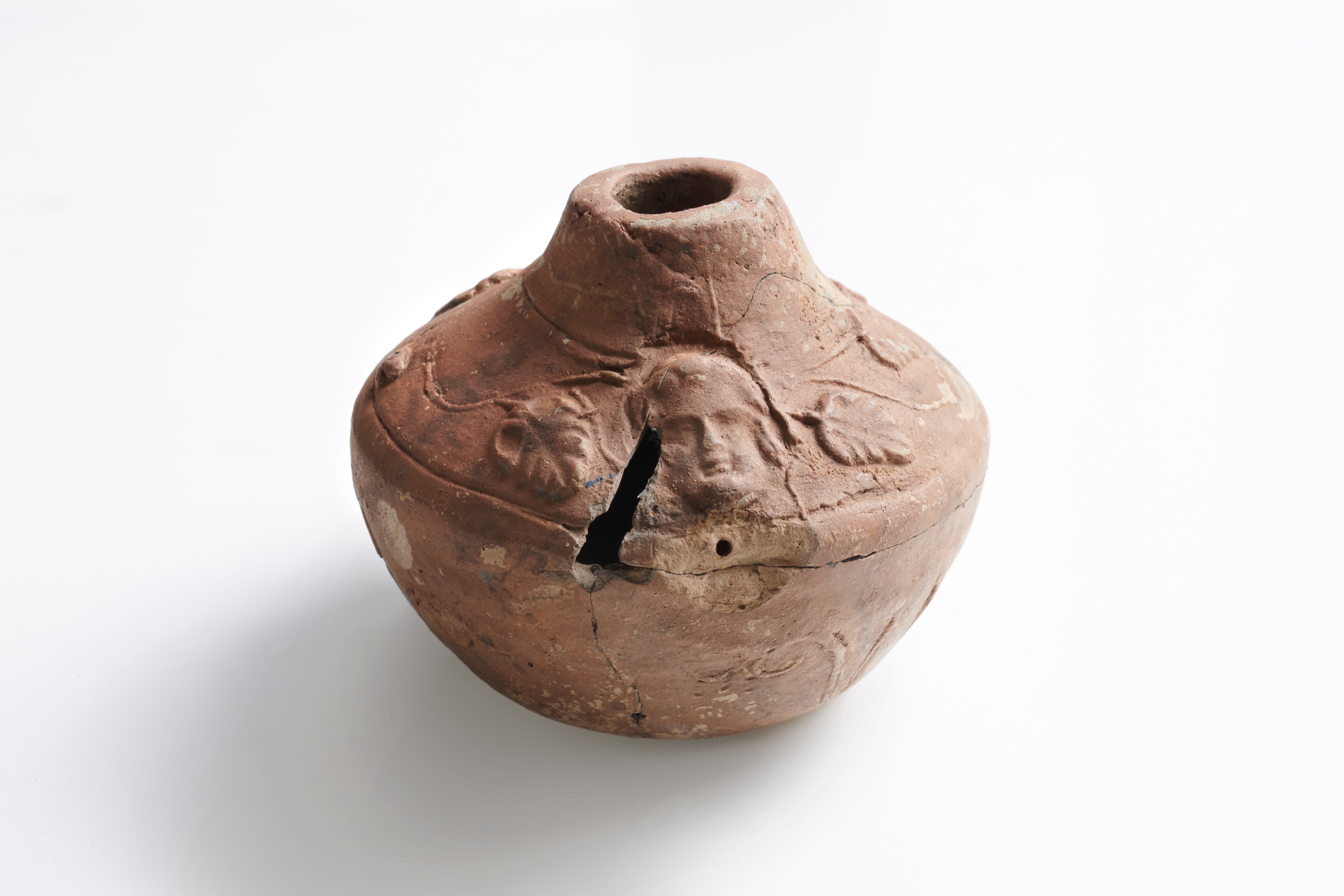 A small Roman pottery vessel with foliage and face