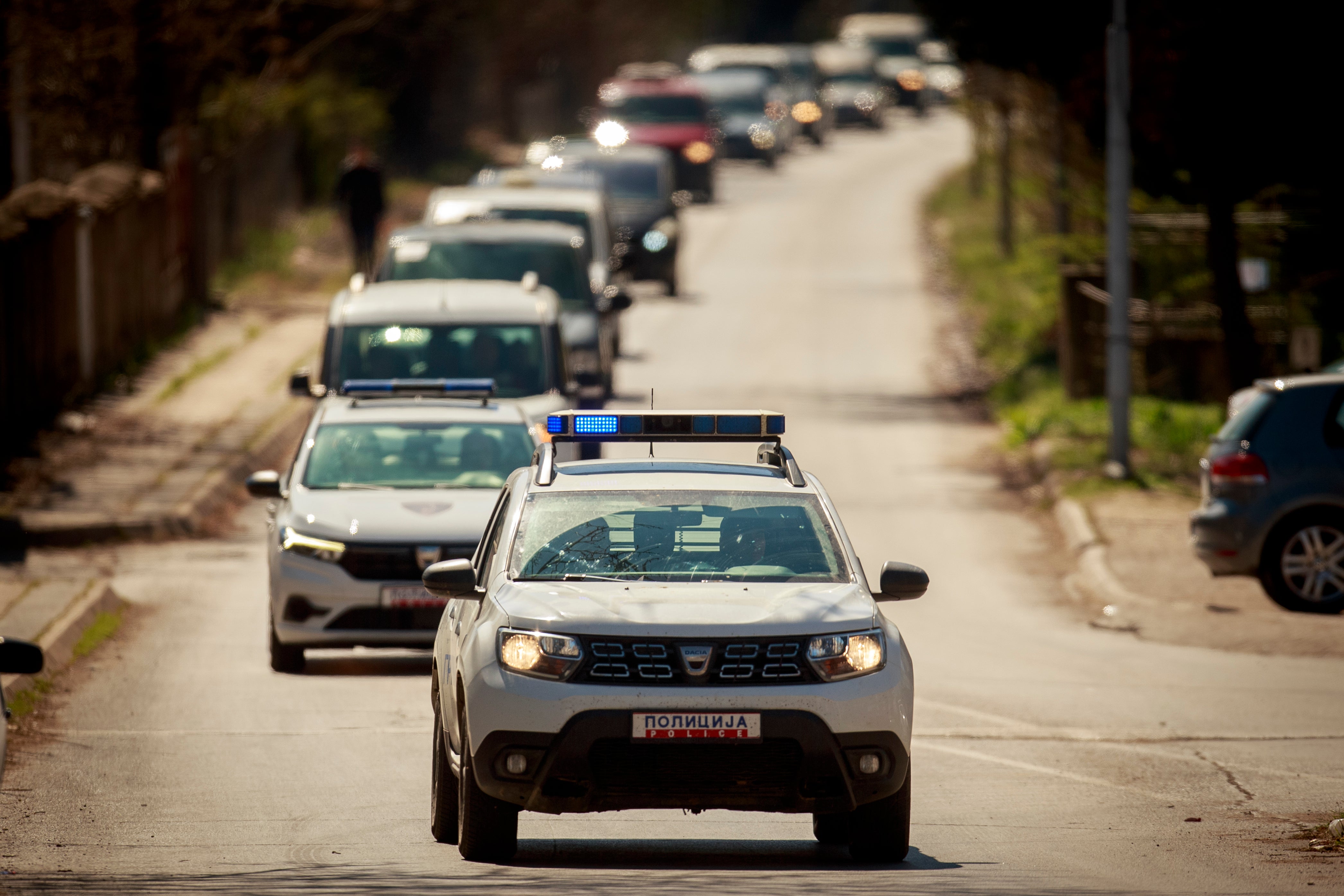 A police car leads a convoy of vehicles ahead of a funeral in the town of Kocani, North Macedonia