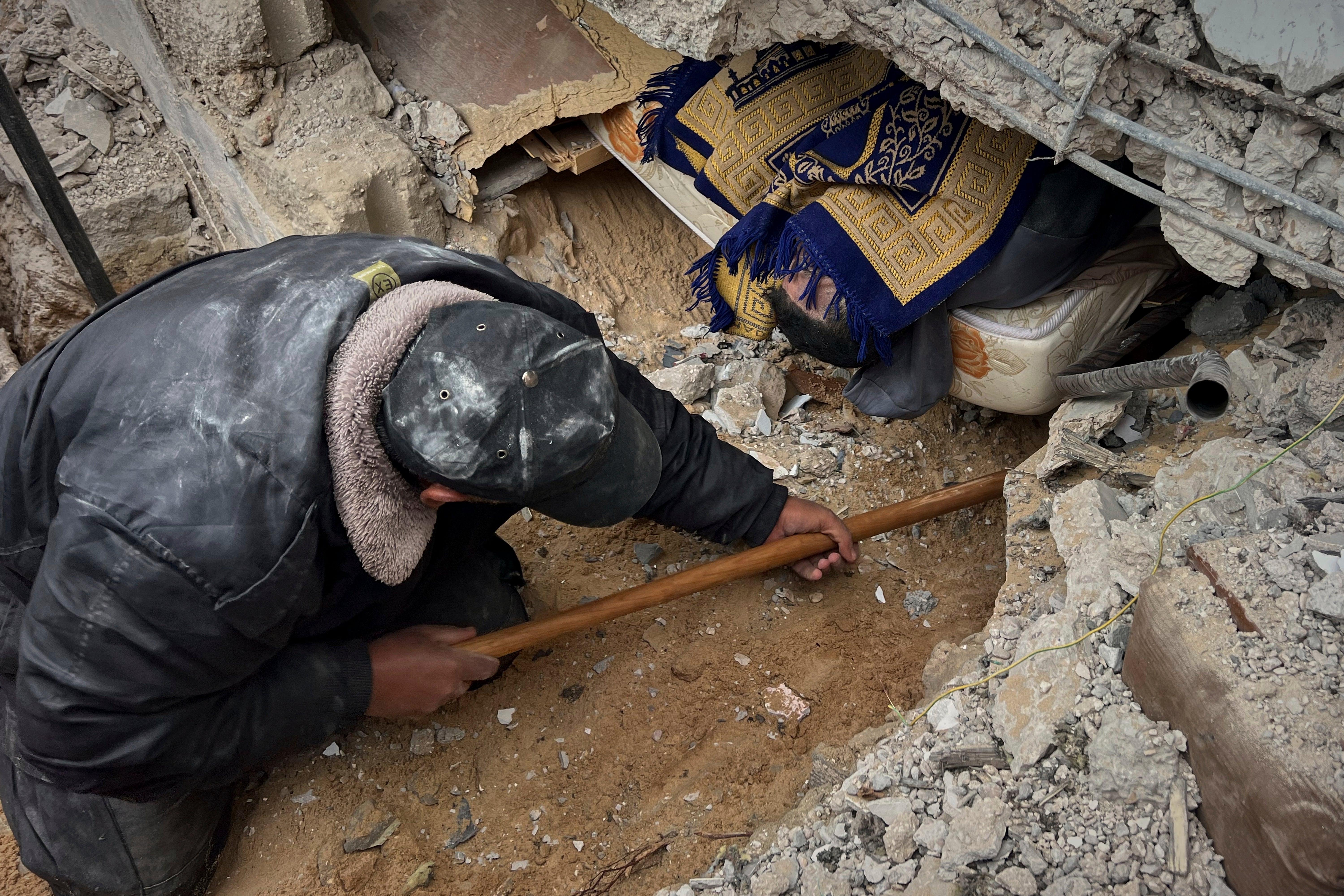 A volunteer attempts to pull the body of a man from the rubble following an Israeli army airstrike in Khan Younis