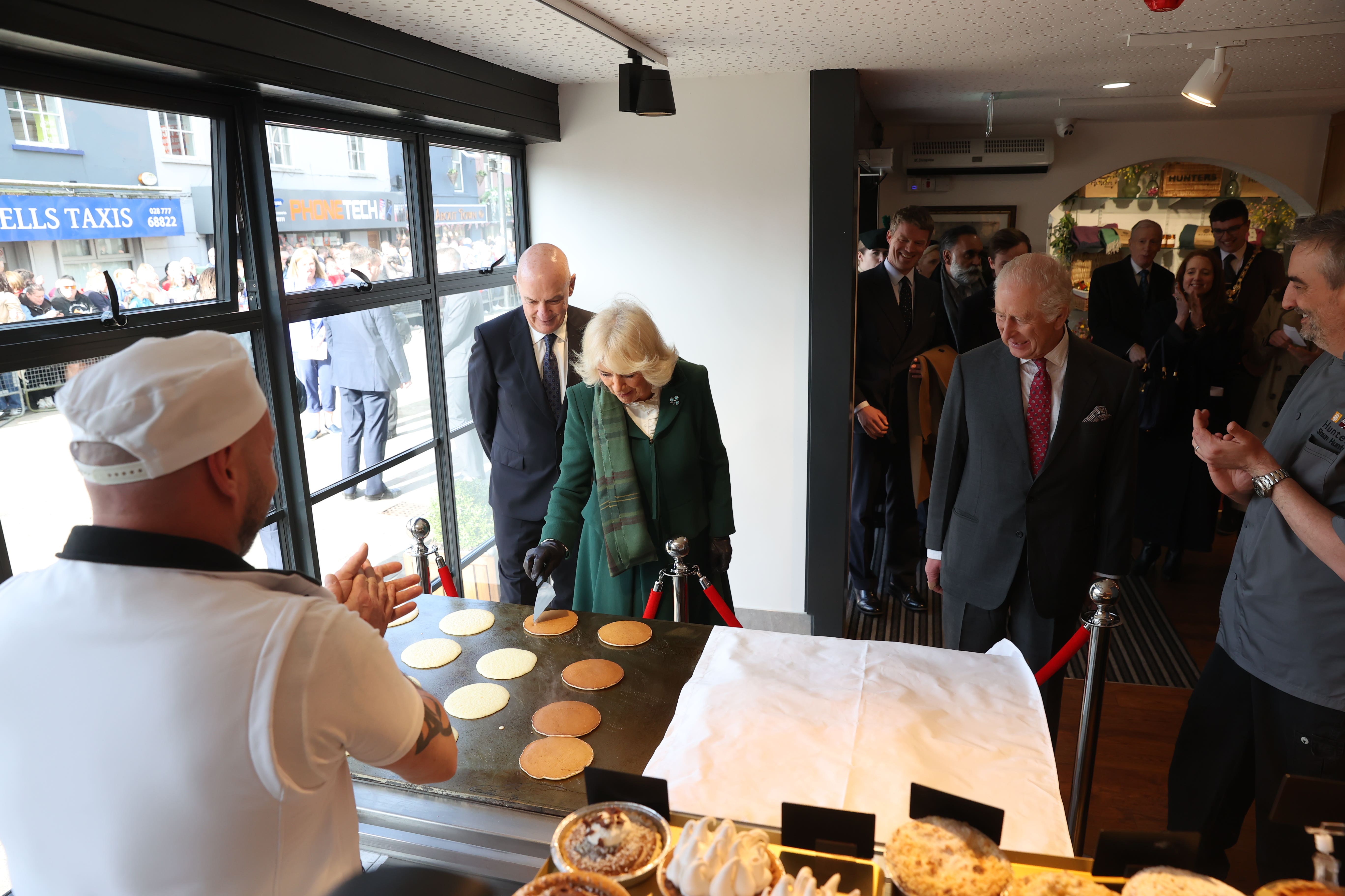 Charles and Camilla help during a demonstration of the production of Ulster Scots Crumpets at Hunters Bakery in Limavady (Liam McBurney/PA)