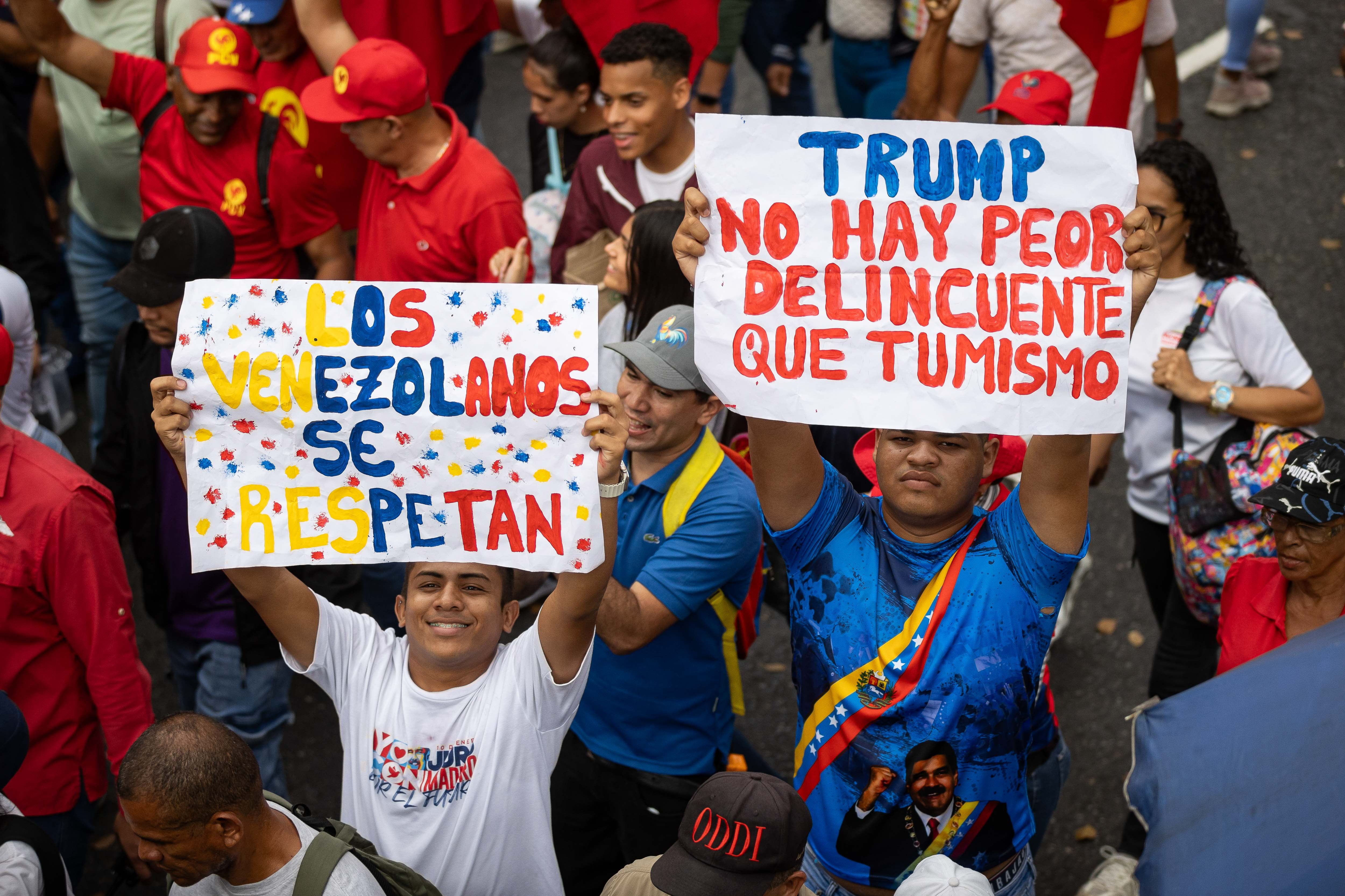 Venezuelan protesters hold signs reading “Venezuelans respect each other” and “Trump, there is no worse criminal than yourself” during a march in defense of Venezuelan immigrants in Caracas March 18