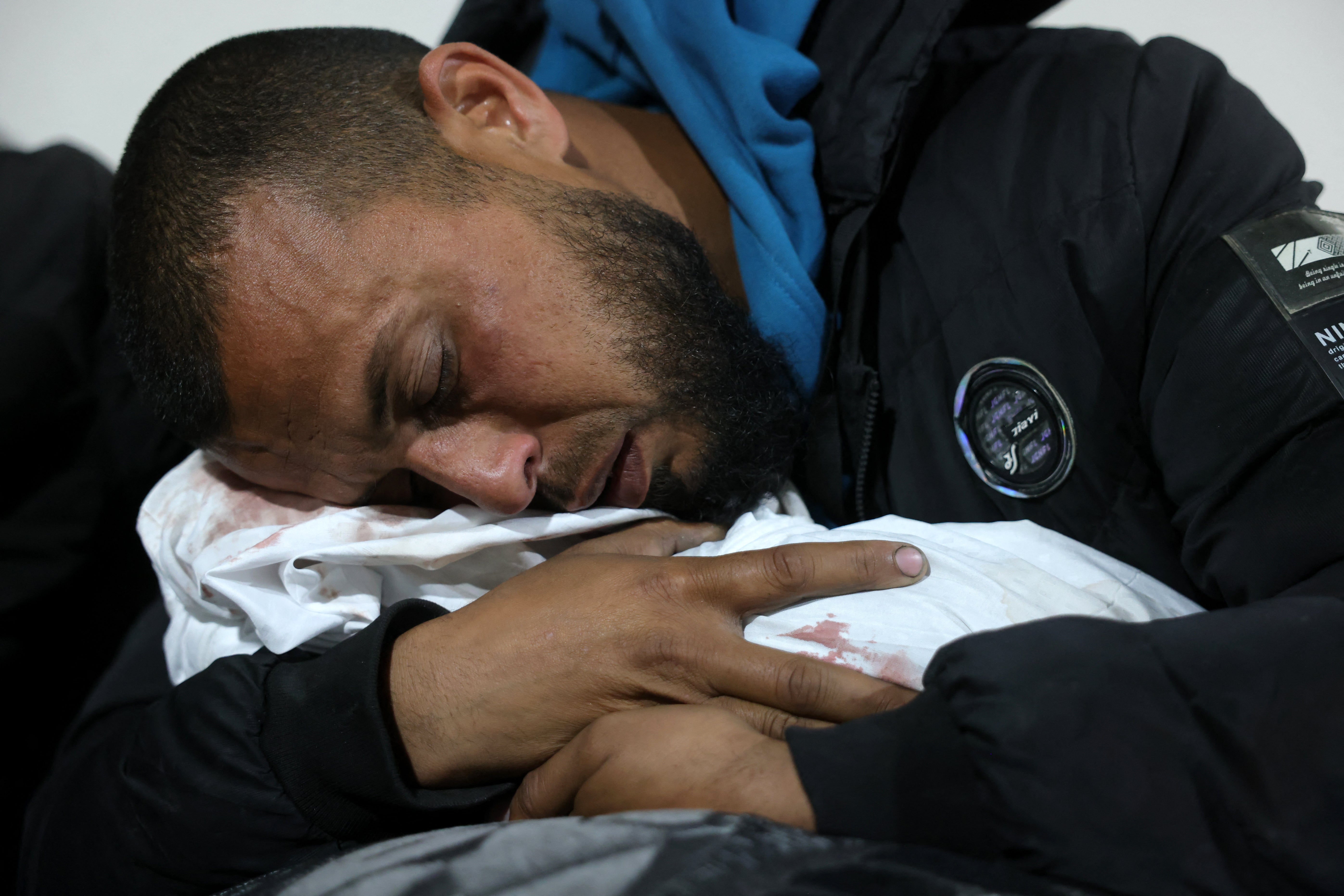 A Palestinian man hugs the body of a baby following Israeli overnight airstrikes in the northern Gaza Strip, at the Indonesian Hospital in Beit Lahia, on March 20