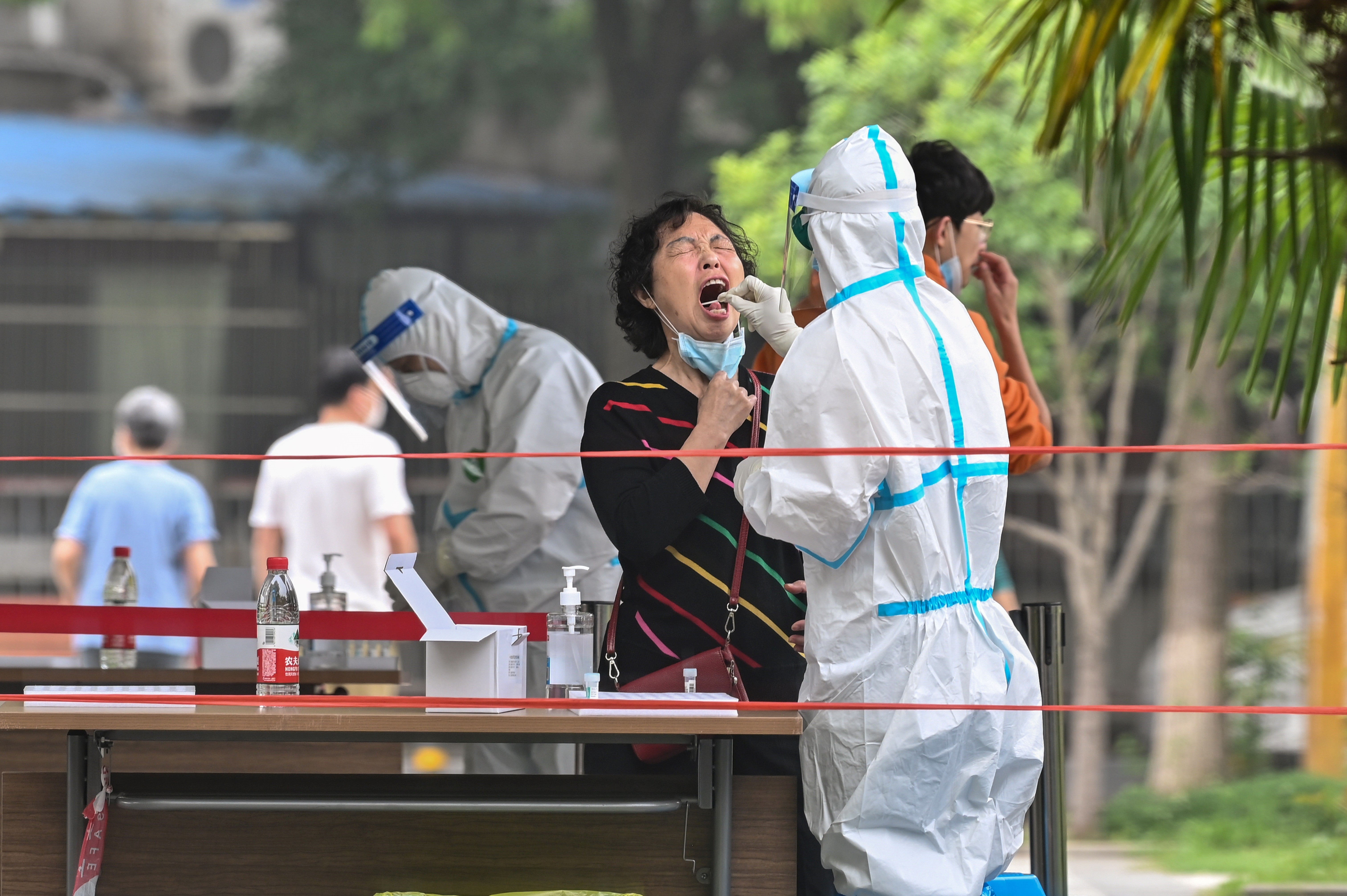 A medical worker takes a swab sample from a patient being tested for Covid