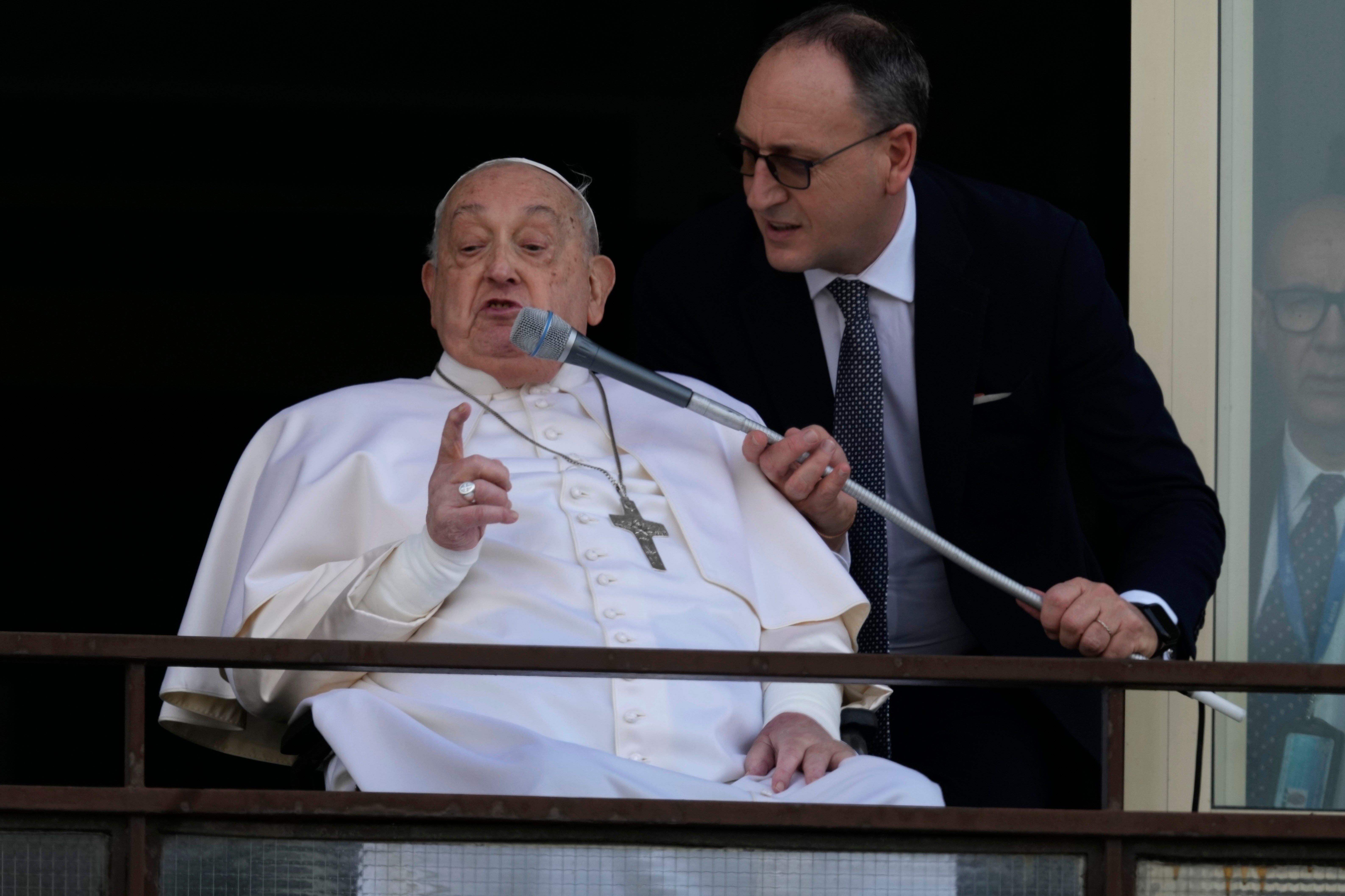 Francis addresses the crowds on a microphone as he appears on a balcony of the Agostino Gemelli Polyclinic