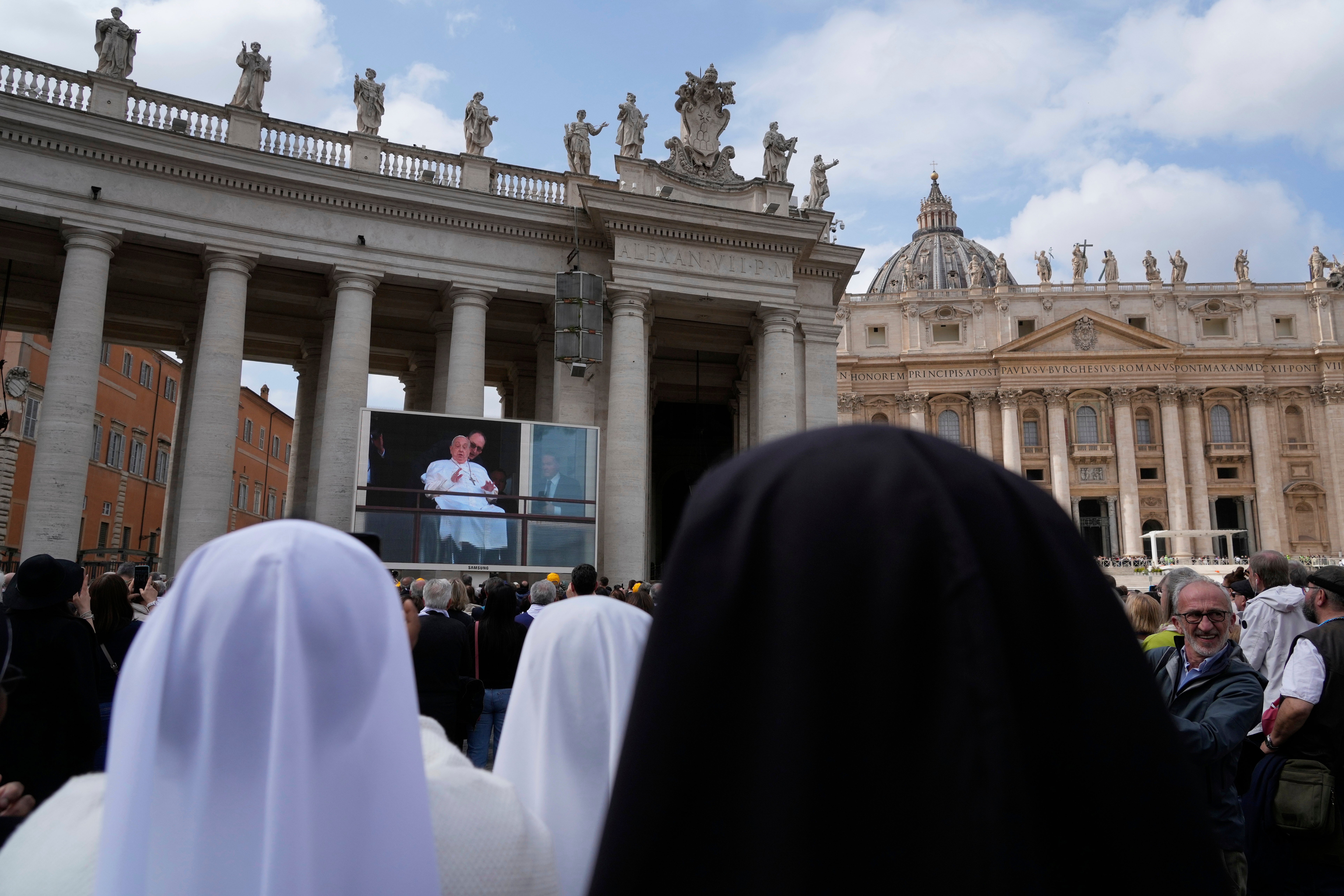 Nuns watch a broadcast of the pope’s appearance on a screen at St Peter’s Square