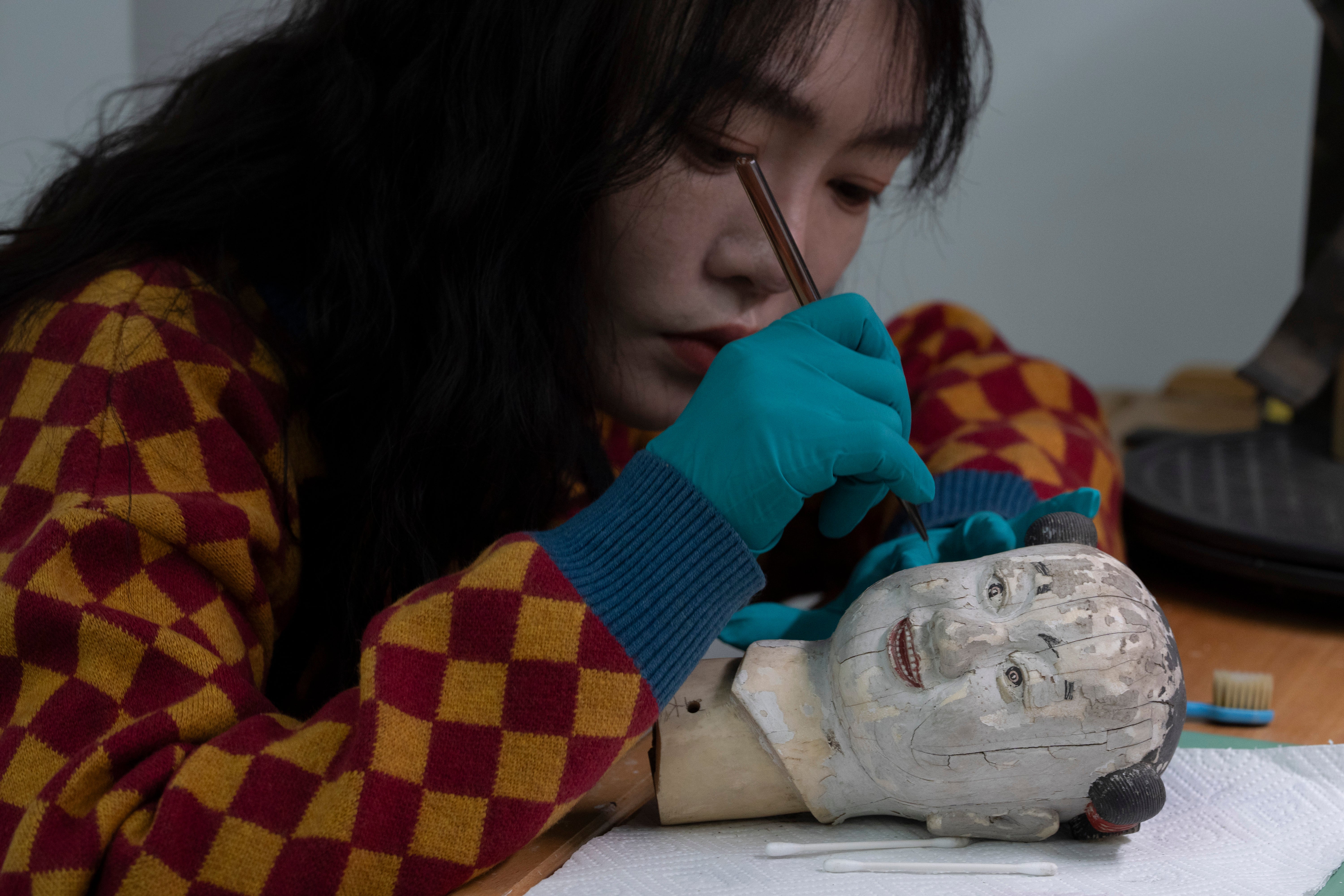 A restorer works on the head of a mechanical doll that manually moves a fan that once kept the imperial family cool on the sprawling compound of the Forbidden City