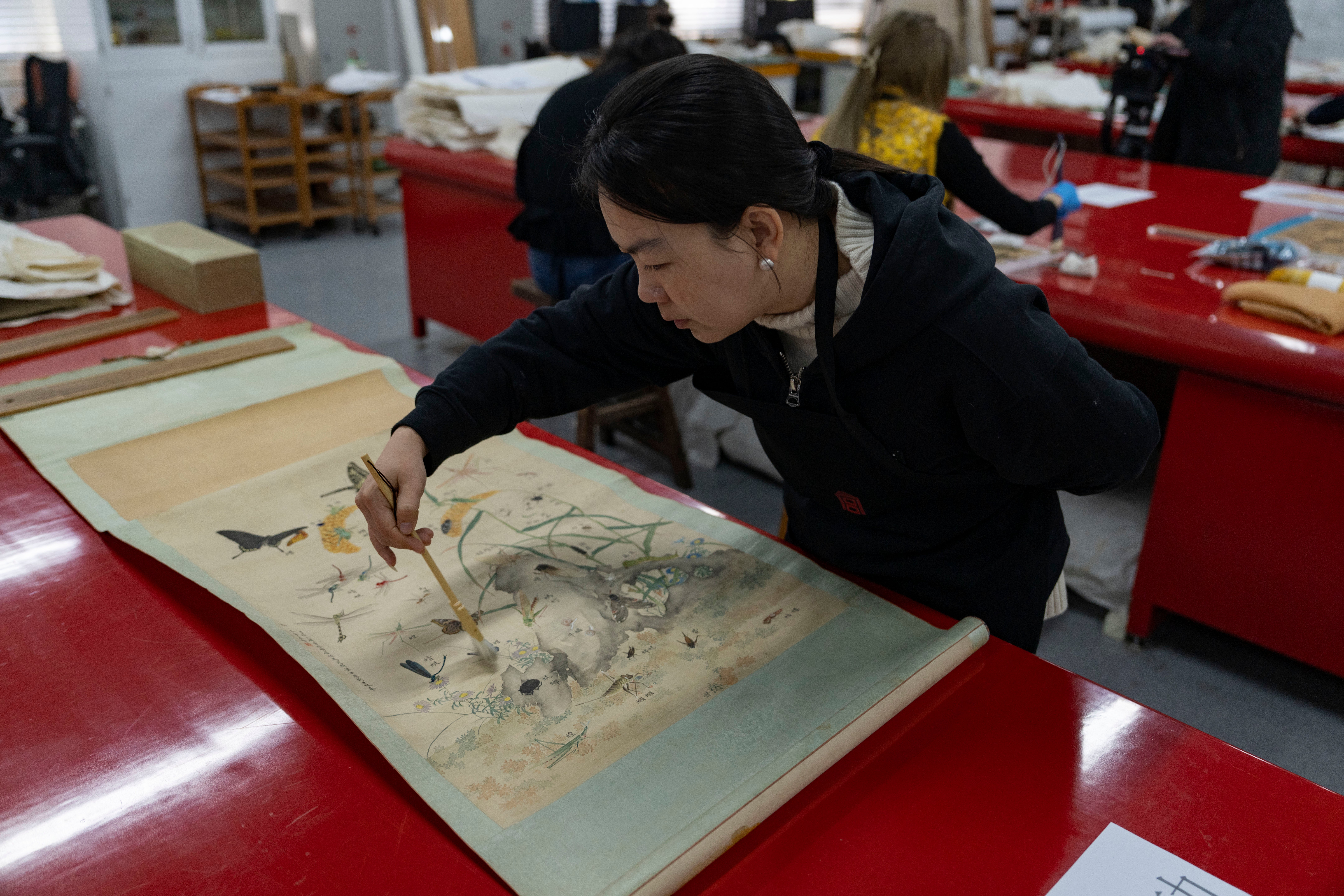 A restorer works on an antique painting in the Forbidden City