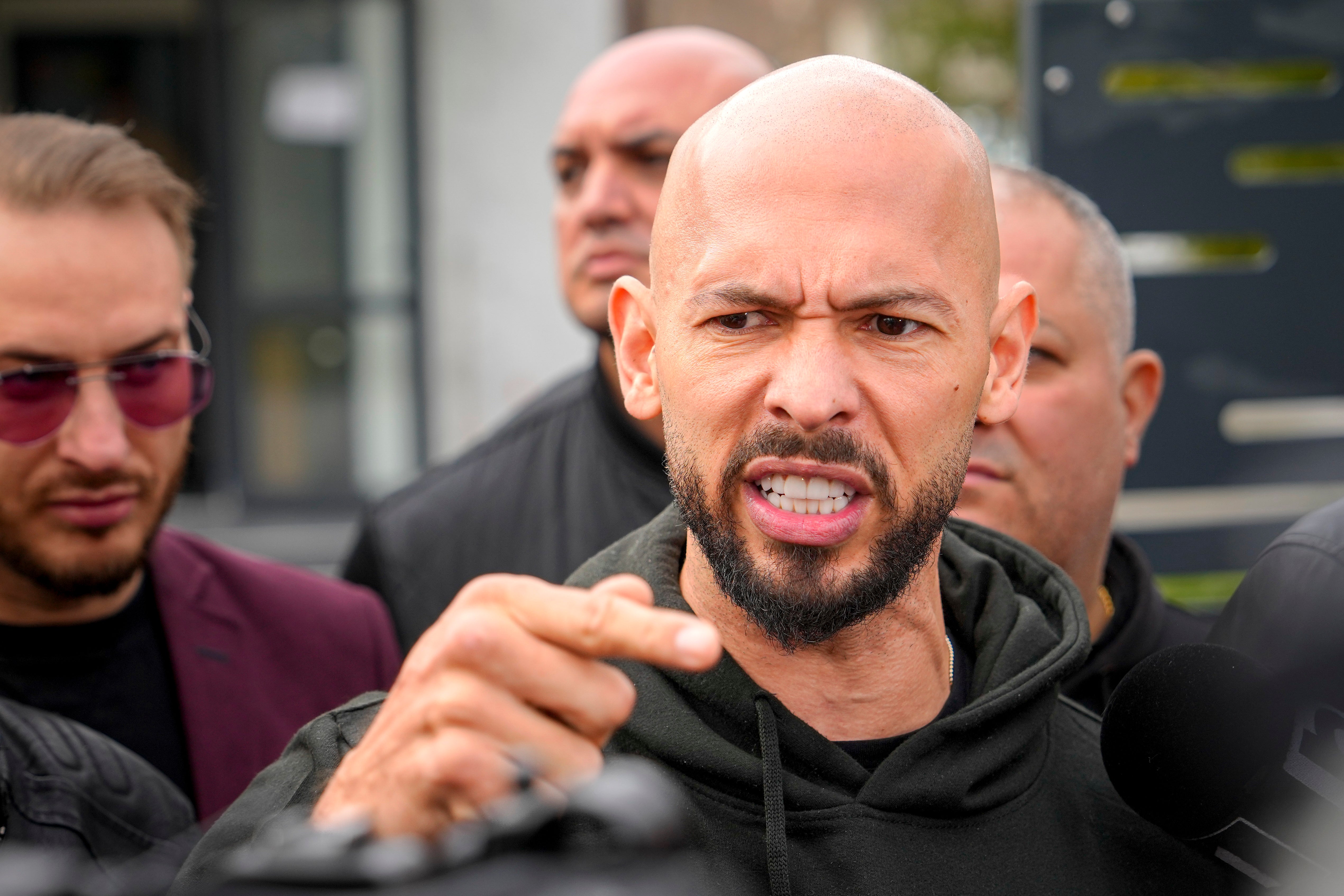 Andrew Tate gestures while speaking to media