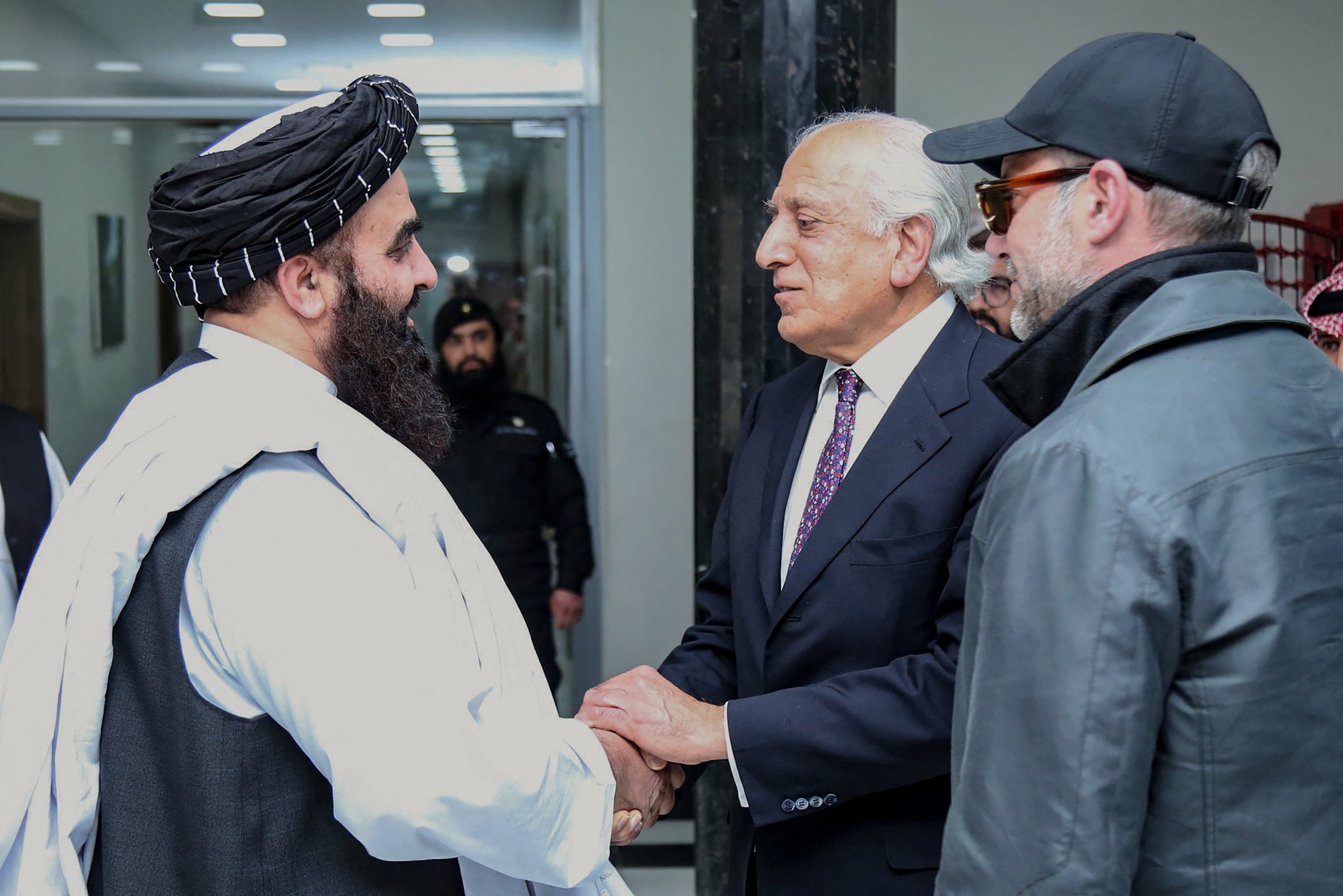 Former US envoy to Afghanistan Zalmay Khalilzad (C) shaking hands with Taliban foreign minister Amir Khan Muttaqi (L) as US official Adam Boehler watches, before their meeting in Kabul