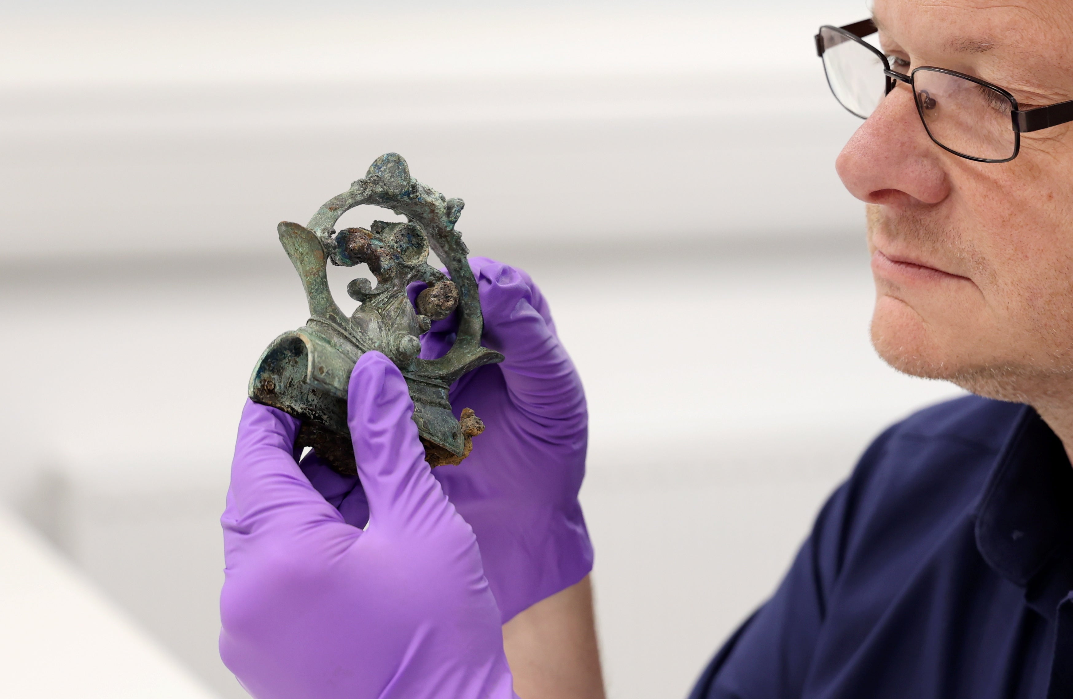 Professor Tom Moore, head of archaeology at Durham University, holds a decorative copper alloy finial from a huge Iron Age hoard discovered in a Yorkshire field