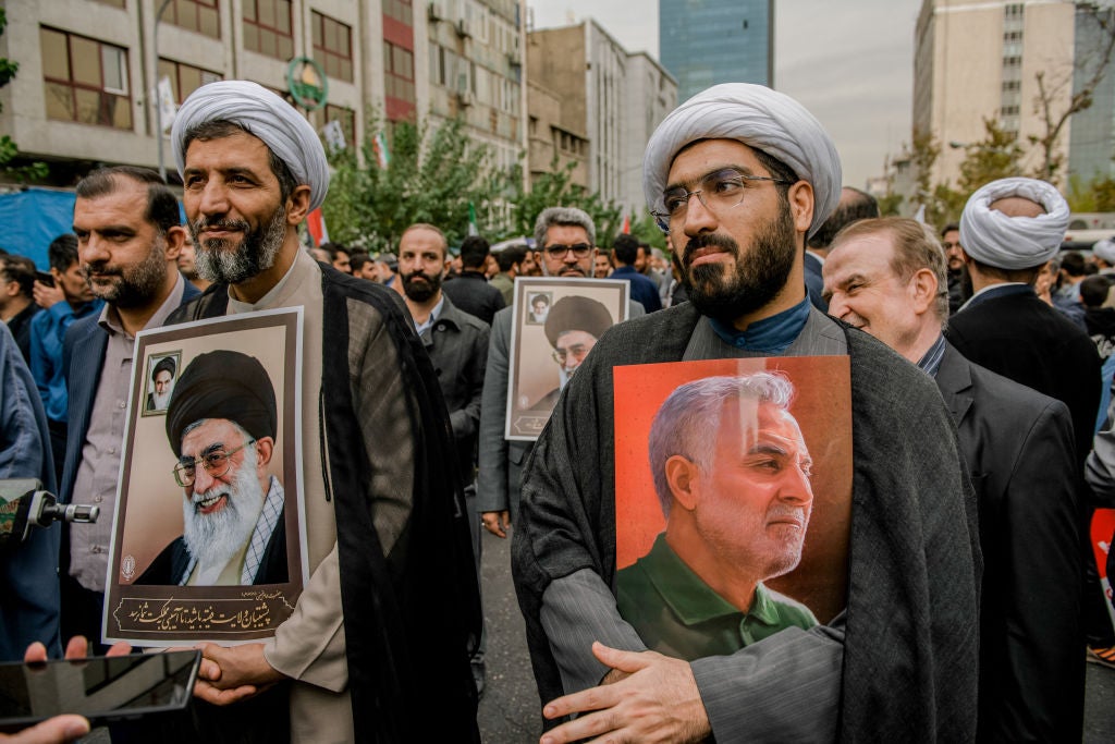 Protesters hold portraits of Iran's Supreme Leader, Ayatollah Khamenei (left) and Qassem Soleimani, right. Soleimani, formerly head of Iran's Revolutionary Guard corps, was killed in Iraq in 2020.