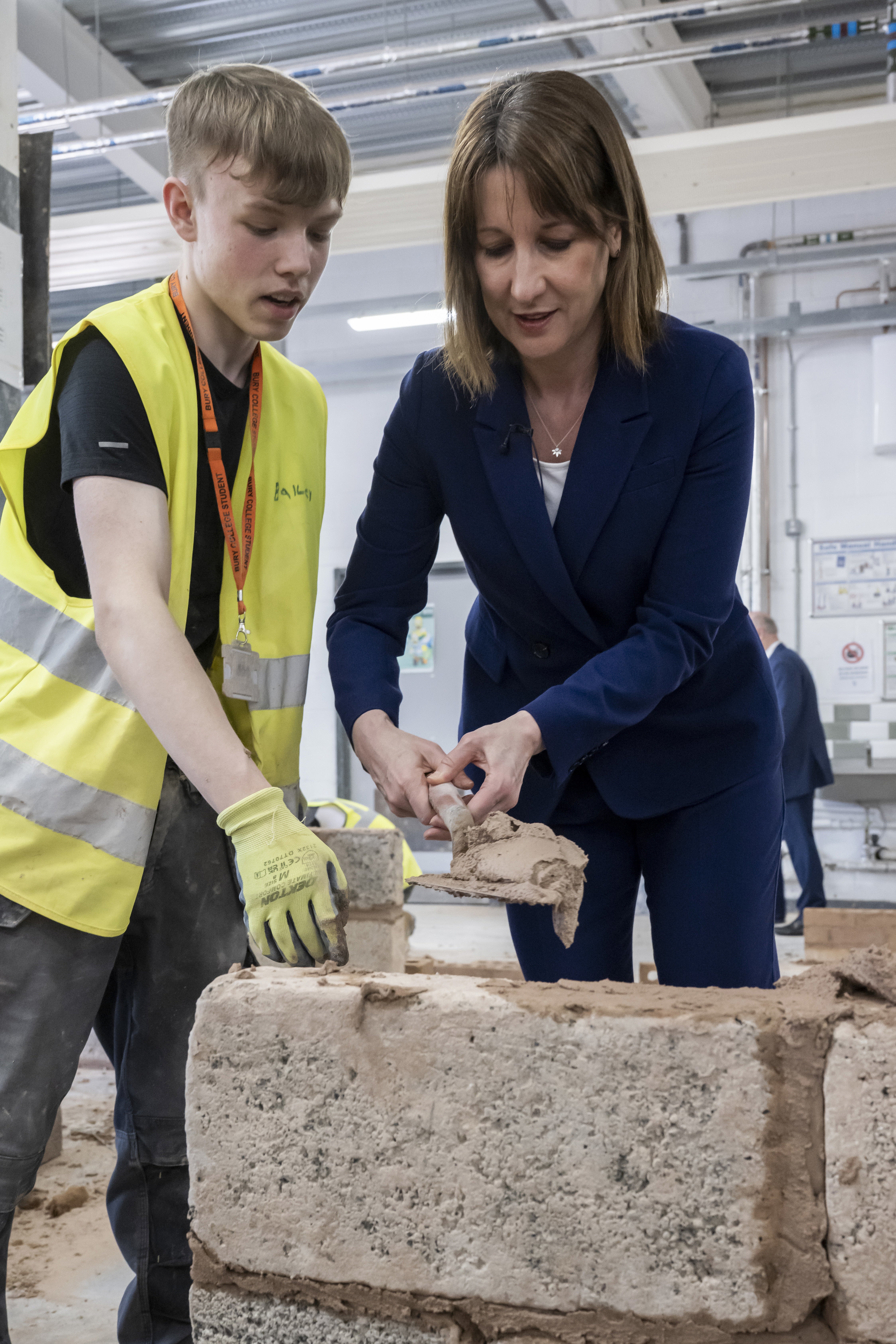 Rachel Reeves lays mortar on to bricks with a student on the bricklaying course during a visit to Bury College (Anthony Delvin/PA)
