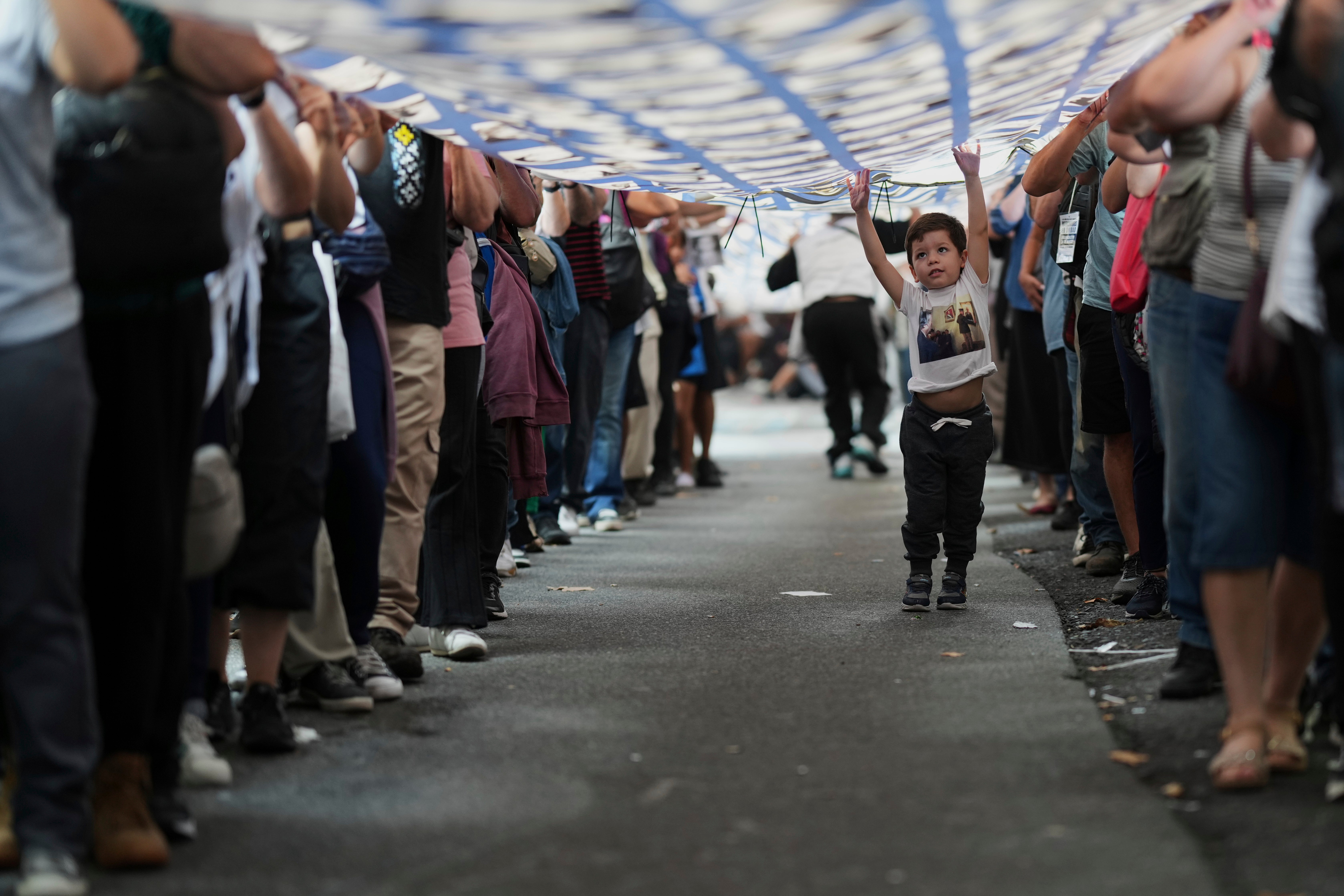 A kid walks nether a banner pinch photos of group who vanished during Argentina's subject dictatorship (1976-1983), during a march commemorating nan day of nan country's 1976 coup, successful Buenos Aires, Argentina