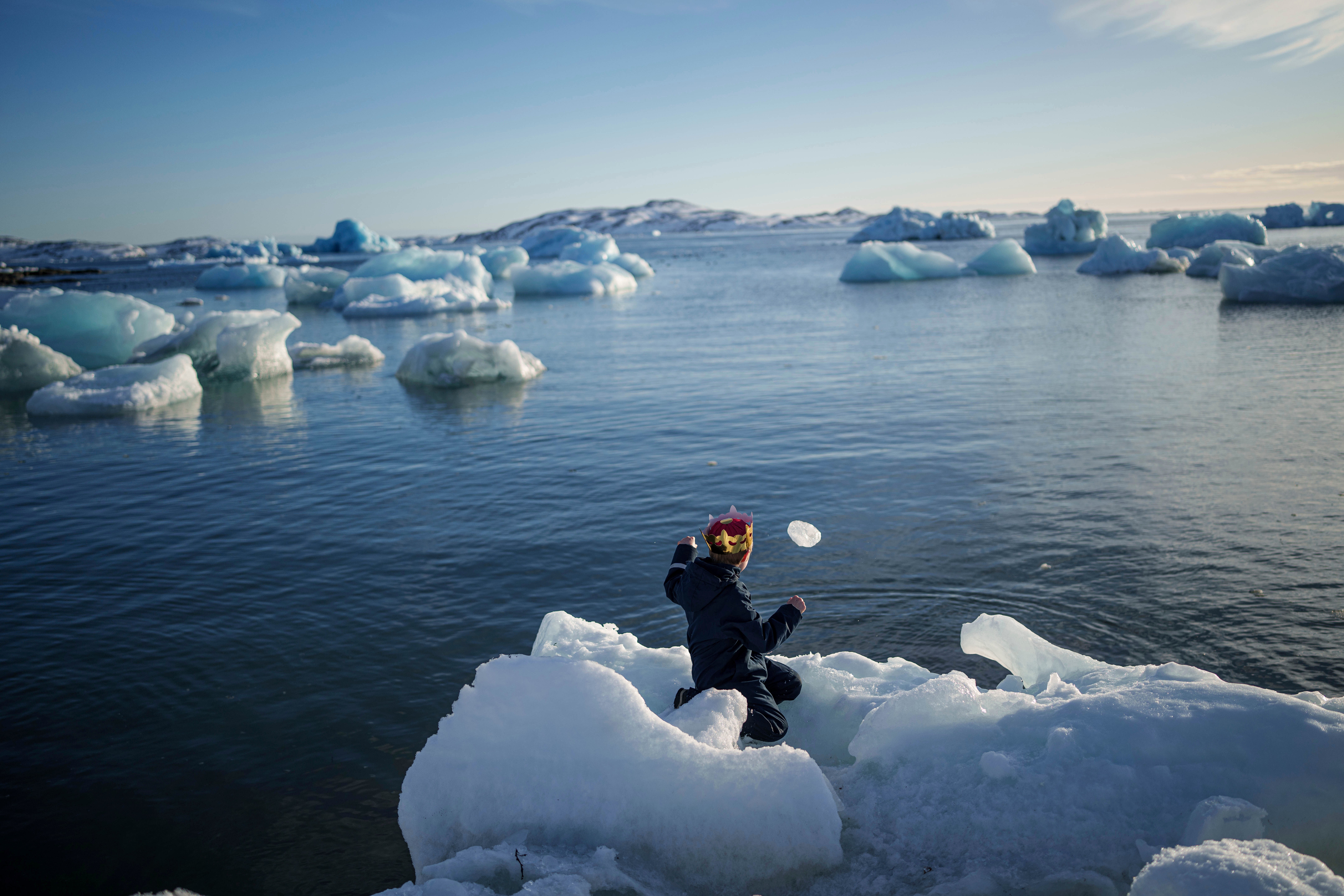 A boy throws ice into the sea in Nuuk, Greenland