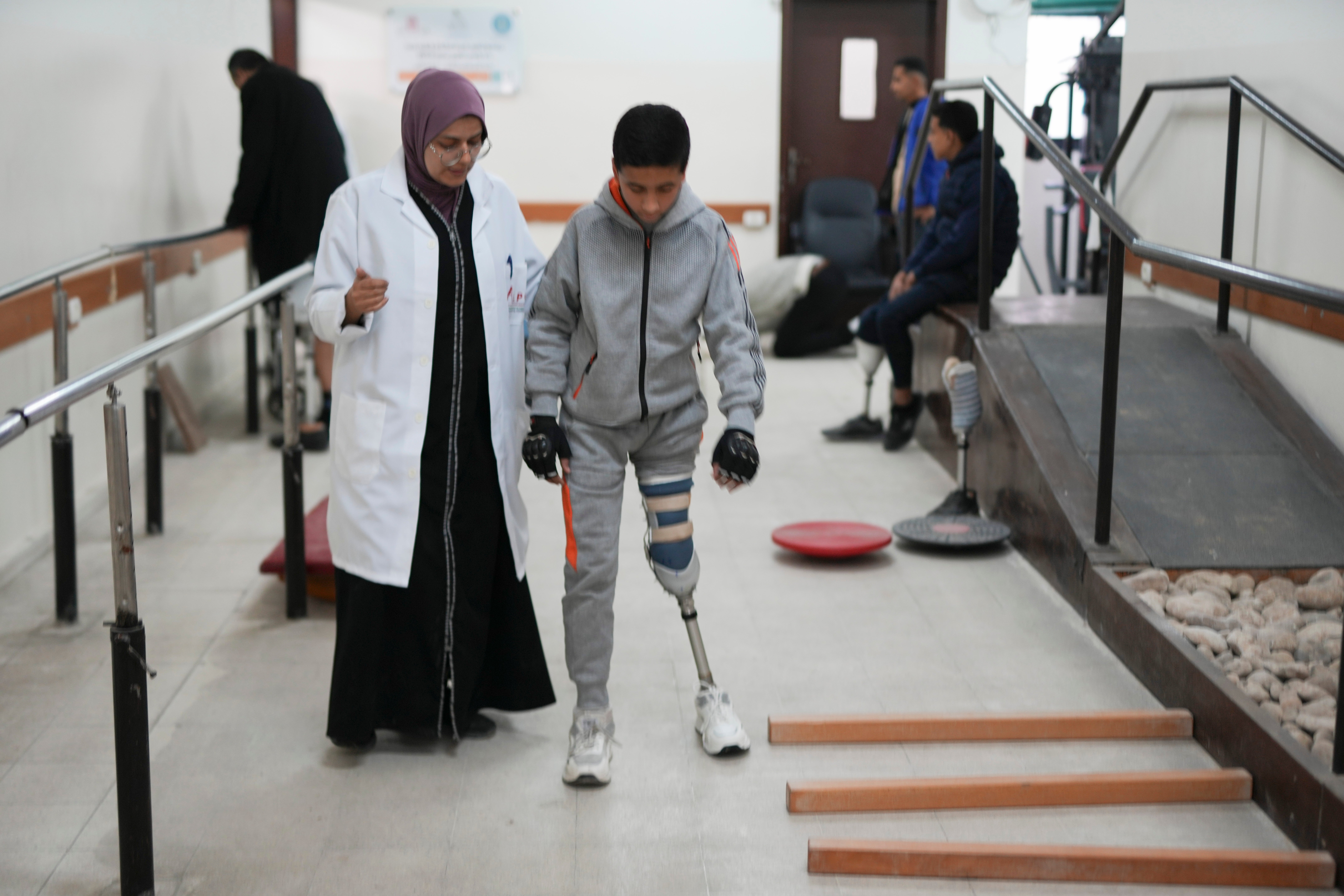 A doctor assists 13-year-old Yamen Asfour as he learns to walk on a prosthetic leg at the Artificial Limbs and Polio Center in Gaza City