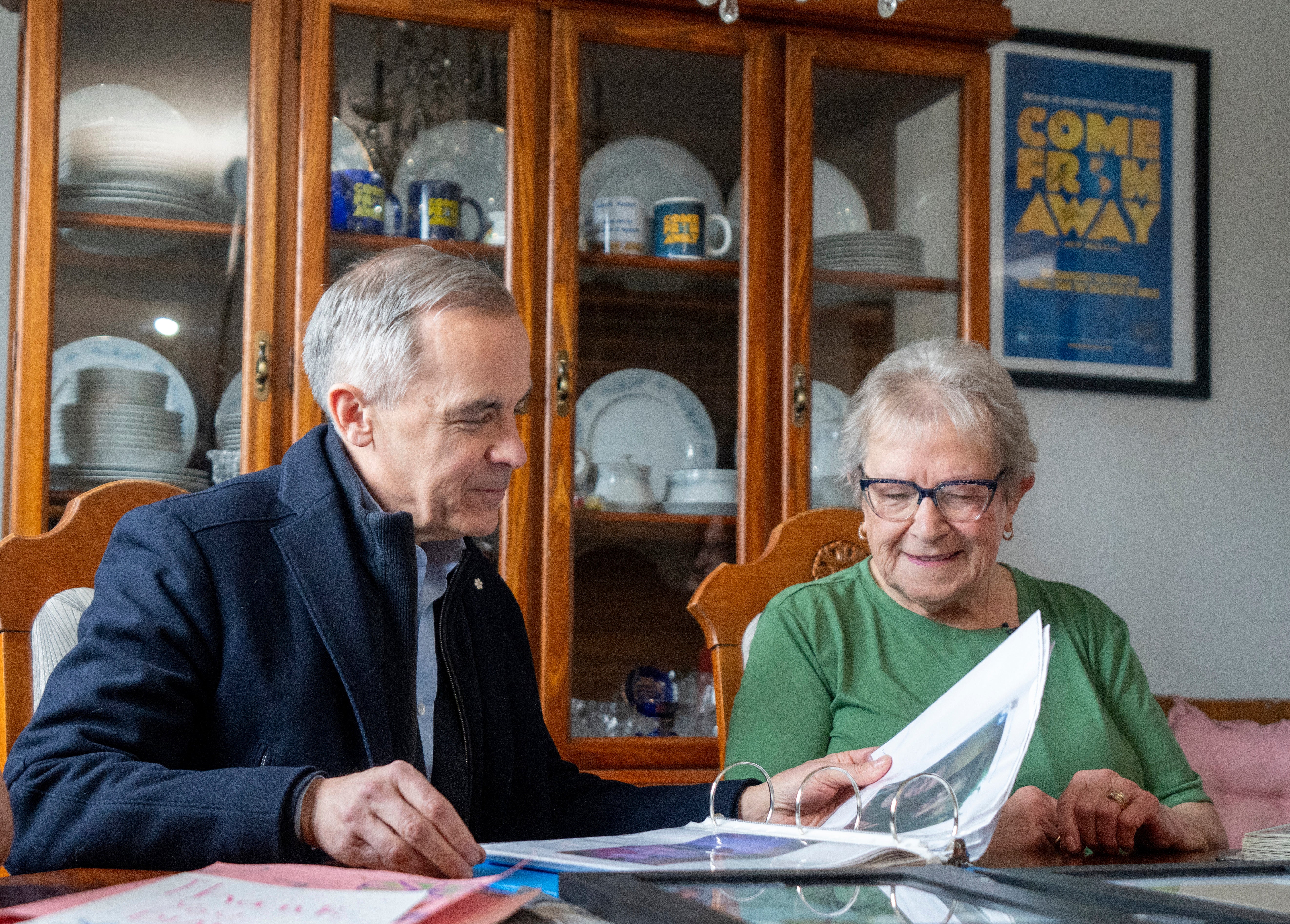 Canada Prime Minister Mark Carney looks through a photo album with Beulah Cooper at her home in Gander