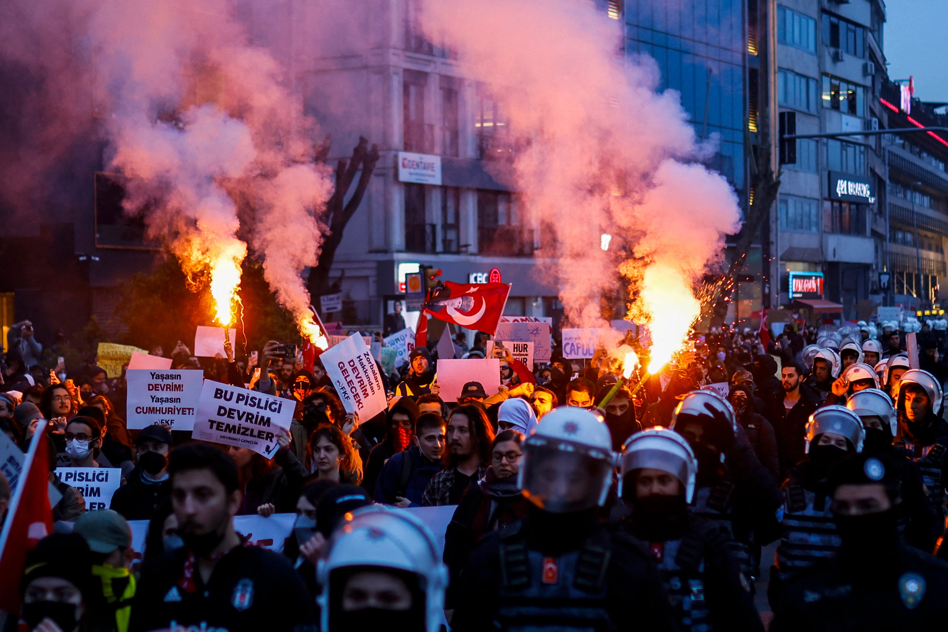 Students burn flares as they walk from the Besiktas district of Istanbul