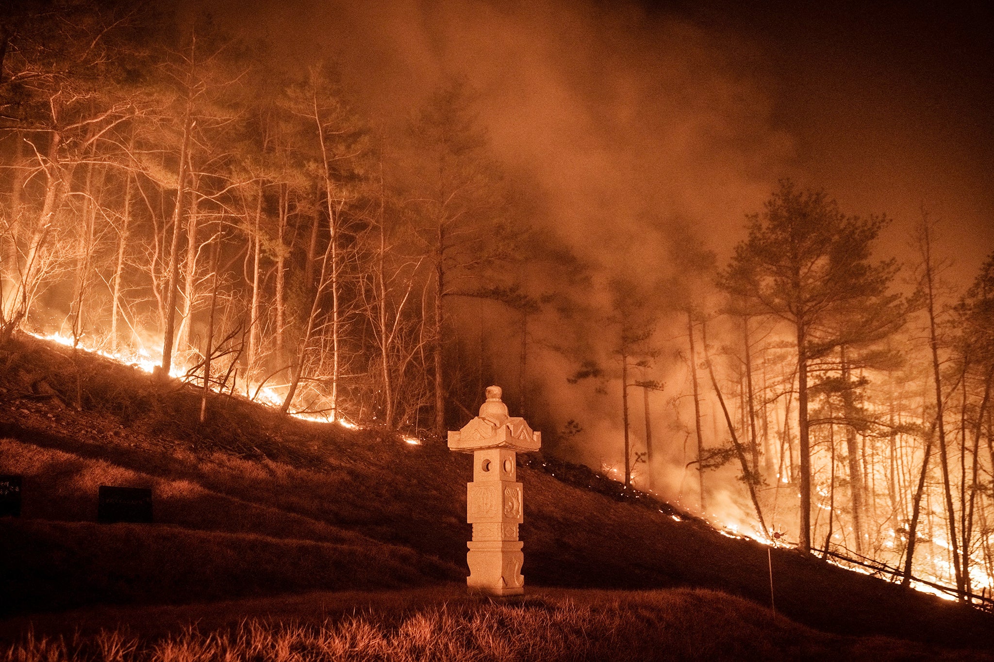 A wildfire is seen next to a stone lantern of family tomb in Andong