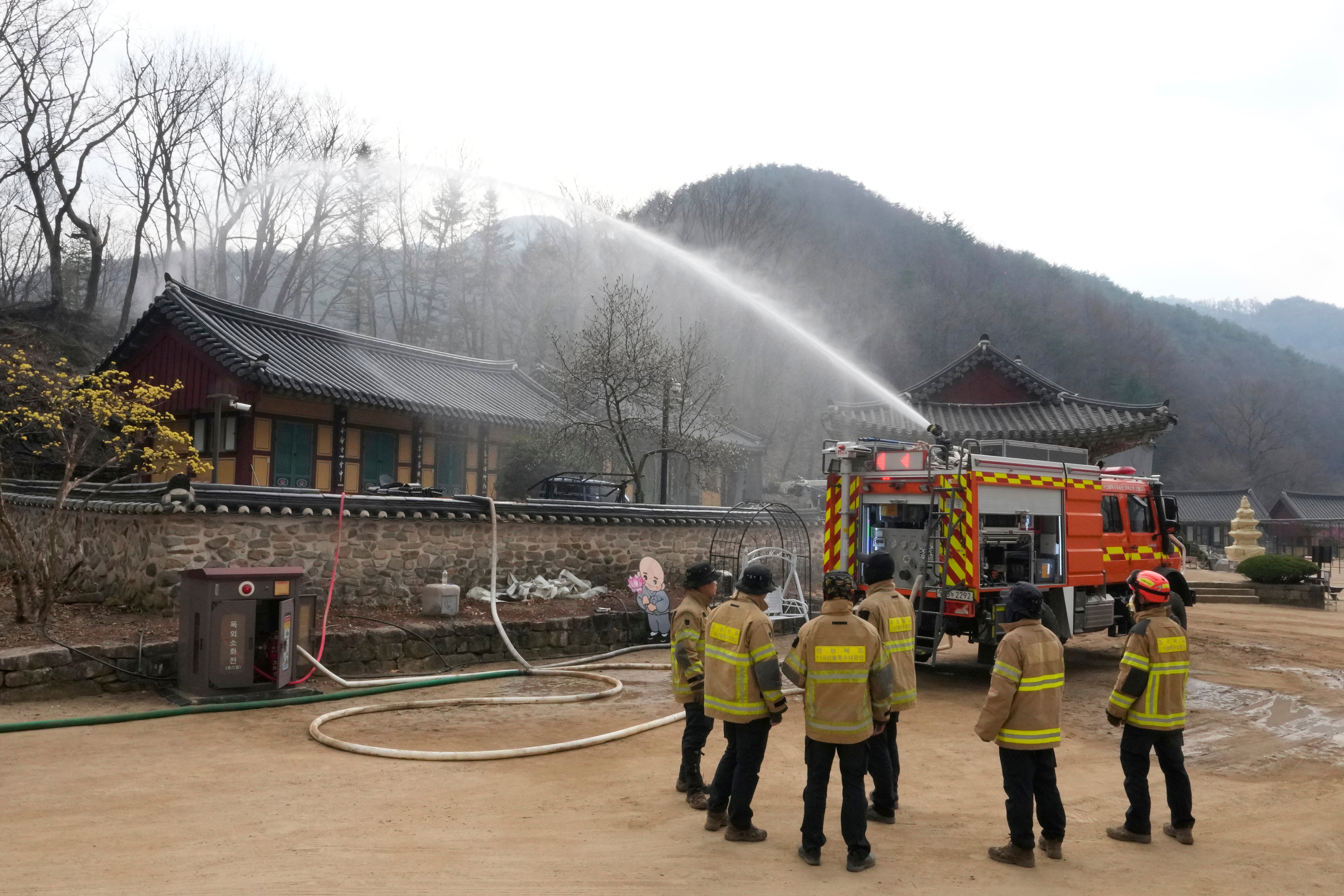 A firefighter vehicle sprays water in preparation for a possible approaching wildfire at a temple in Cheongsong, South Korea