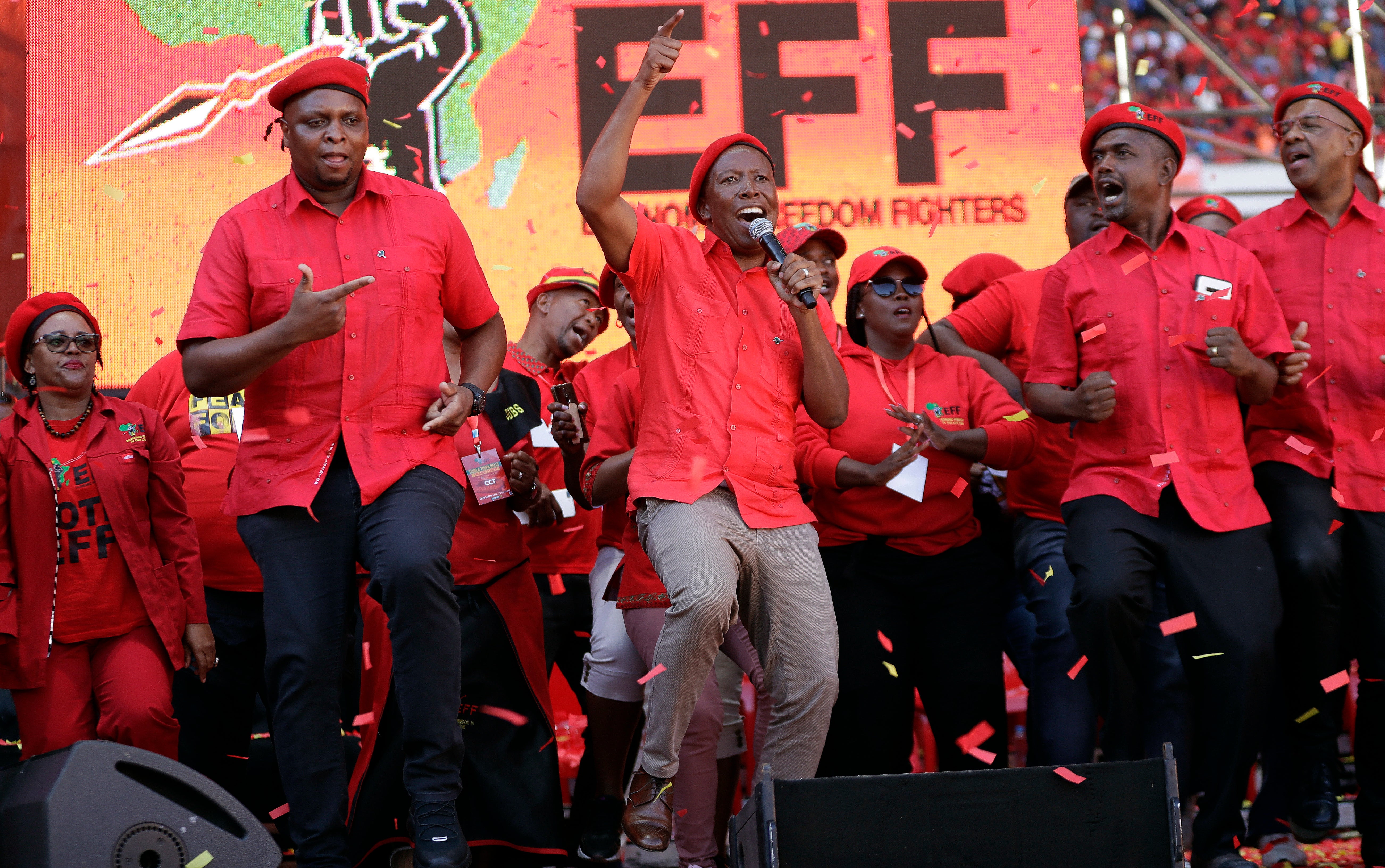 Leader of the Economic Freedom Fighters (EFF) party, Julius Malema, centre, with party members sing and dance after addressing supporters during an election rally at Orlando Stadium in Soweto, South Africa, Sunday, May 5, 2019. (AP Photo/Themba Hadebe, File)