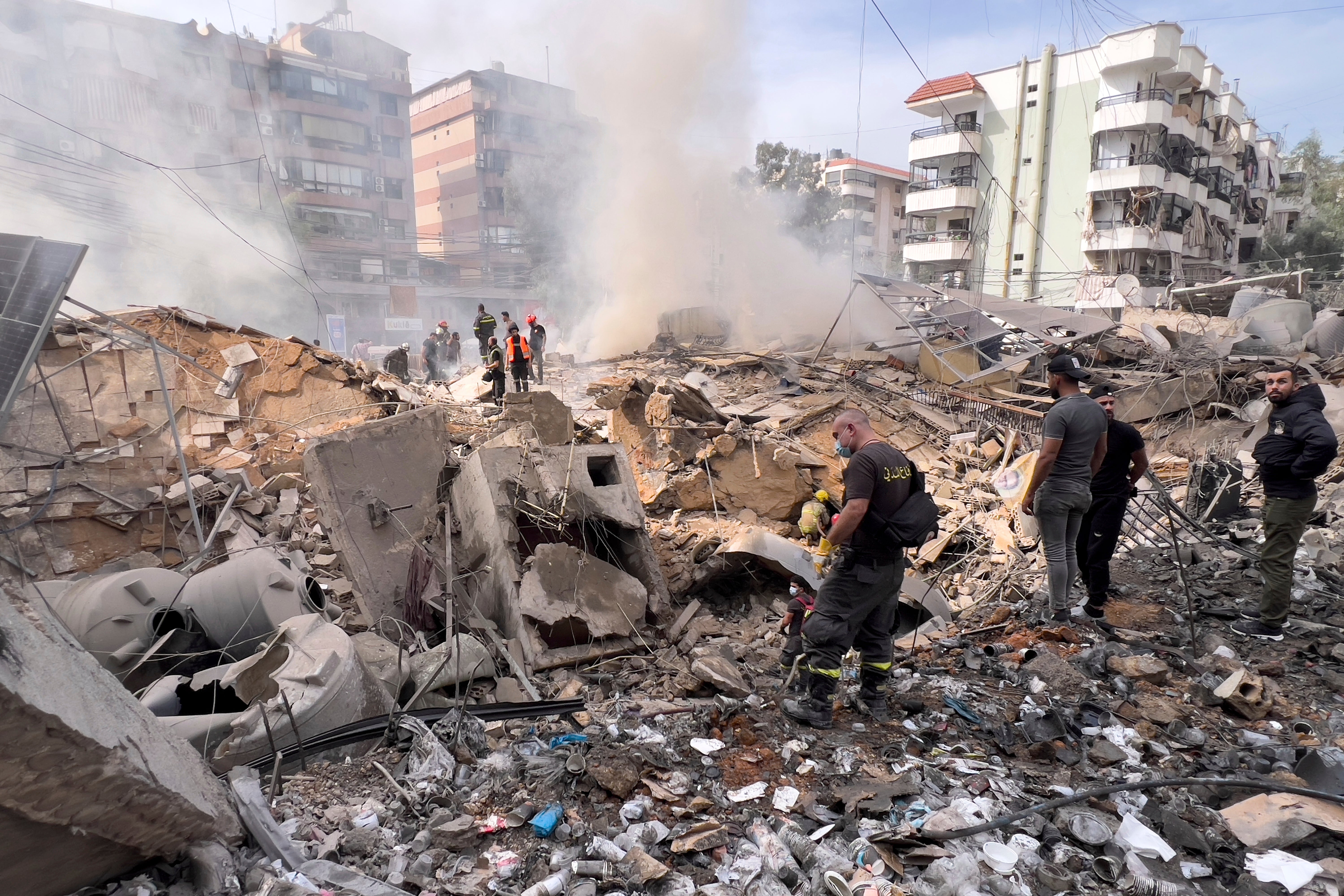 Firefighters inspect the area after an Israeli strike on the suburb of Dahiye, Beirut