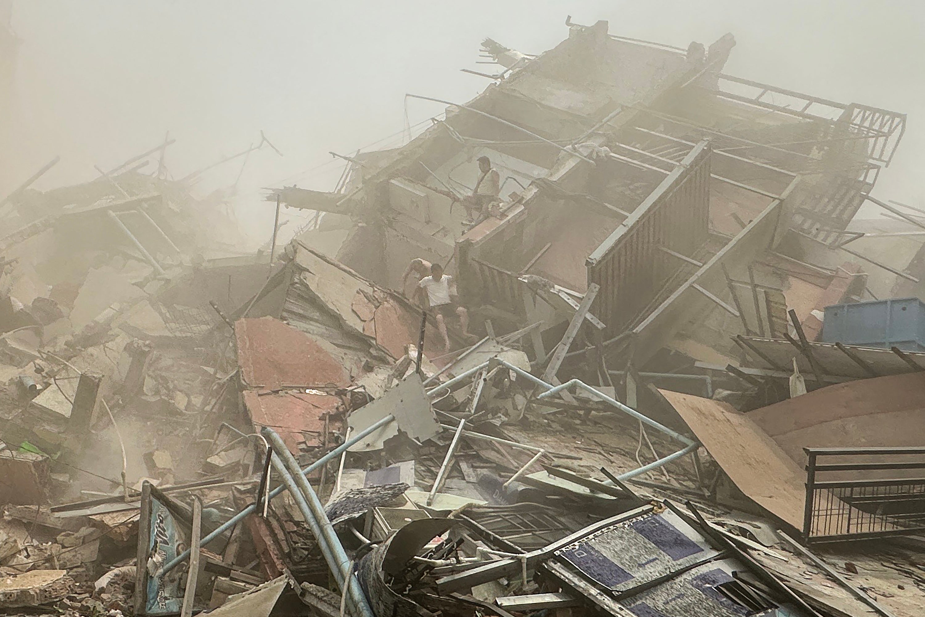 People inspect the debris of a collapsed building in Mandalay