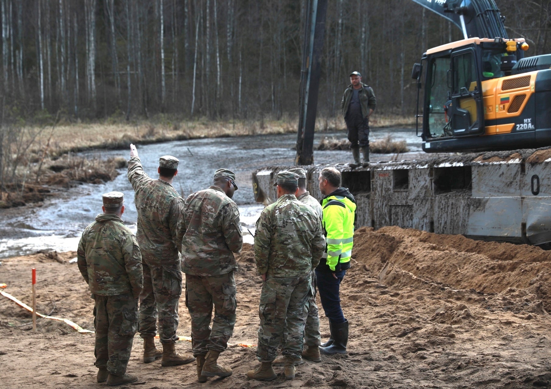 U.S. Army soldiers from the 1st Armored Brigade Combat Team, 3rd Infantry Division, along with Lithuanian Army and emergency services personnel, discuss their plan to recover four U.S. soldiers in a U.S. Army M88 Hercules submerged under several meters of water in a swamp near a training area near Pabadre, Lithuania