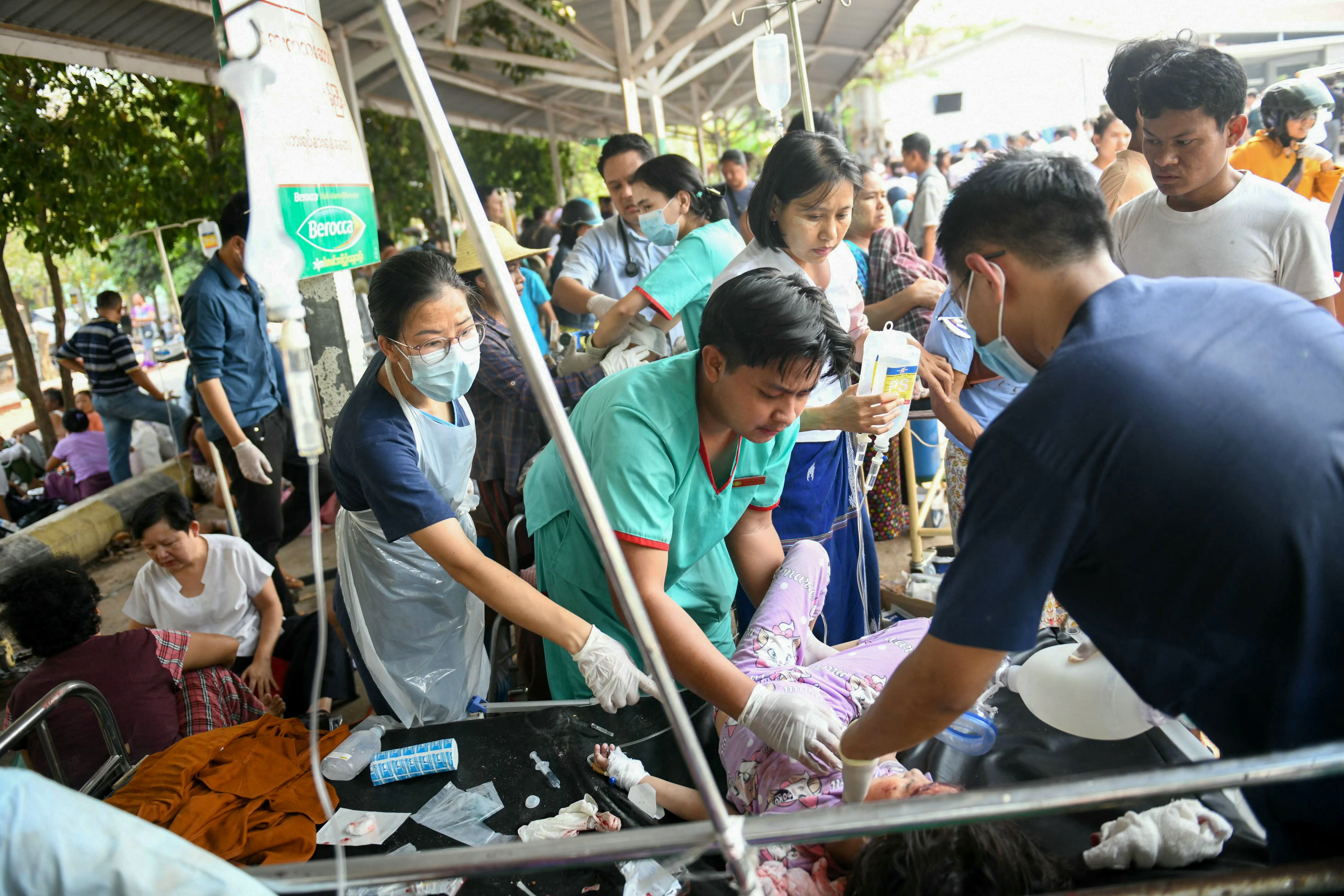 Medical workers treat a earthquake survivor on a bed in the compound of a hospital in Naypyidaw, the capital of Myanmar