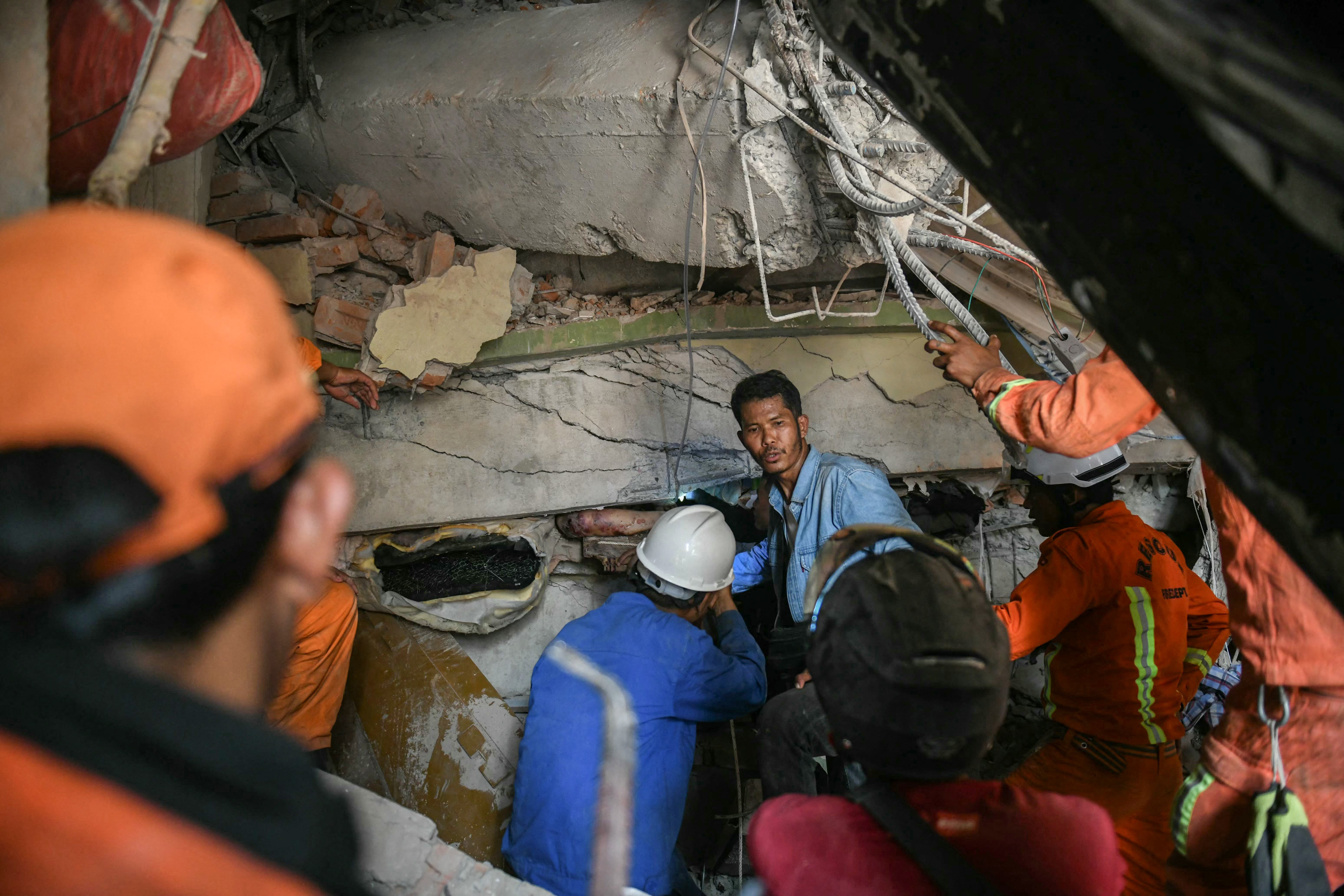 Rescue workers attempt to free a resident trapped under the rubble of the destroyed Sky Villa Condominium development in Mandalay