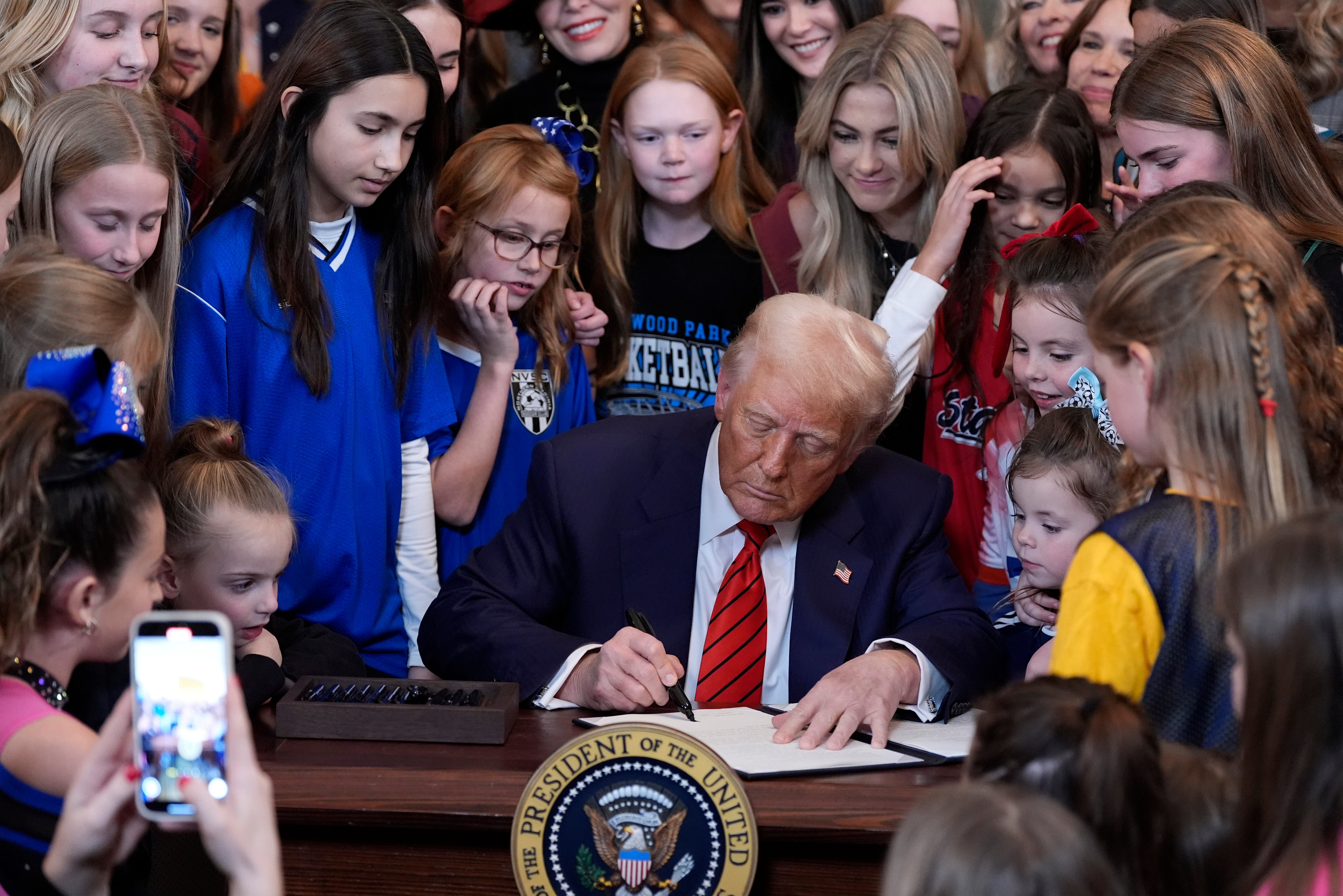 President Donald Trump signs an executive order barring transgender female athletes from competing in women's or girls' sporting events, in the East Room of the White House, Feb. 5, 2025