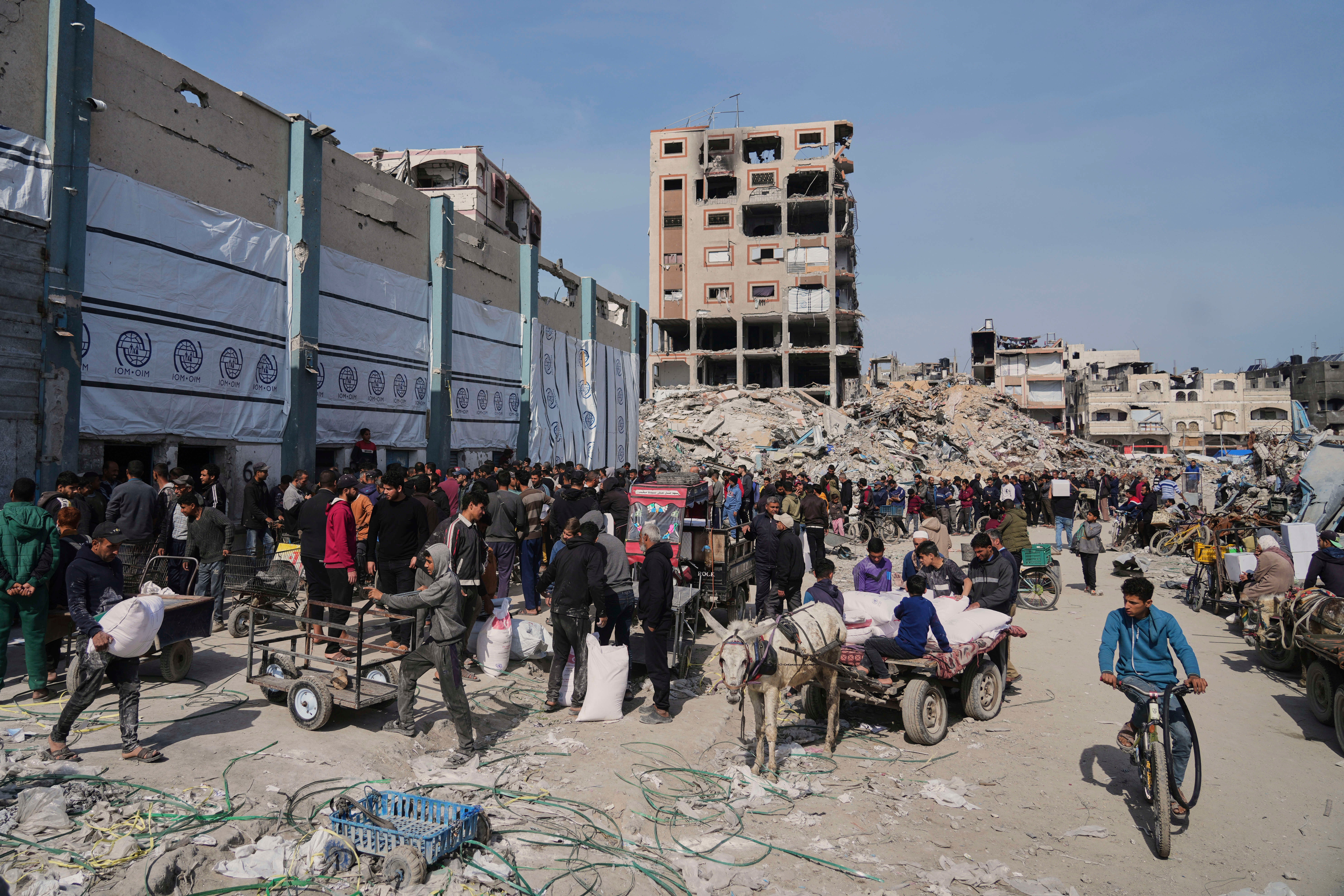 Palestinians receive bags of flour and other humanitarian aid distributed by UNRWA, the U.N. agency helping Palestinian refugees in Jabaliya, Gaza Strip on Tuesday, March 25, 2025