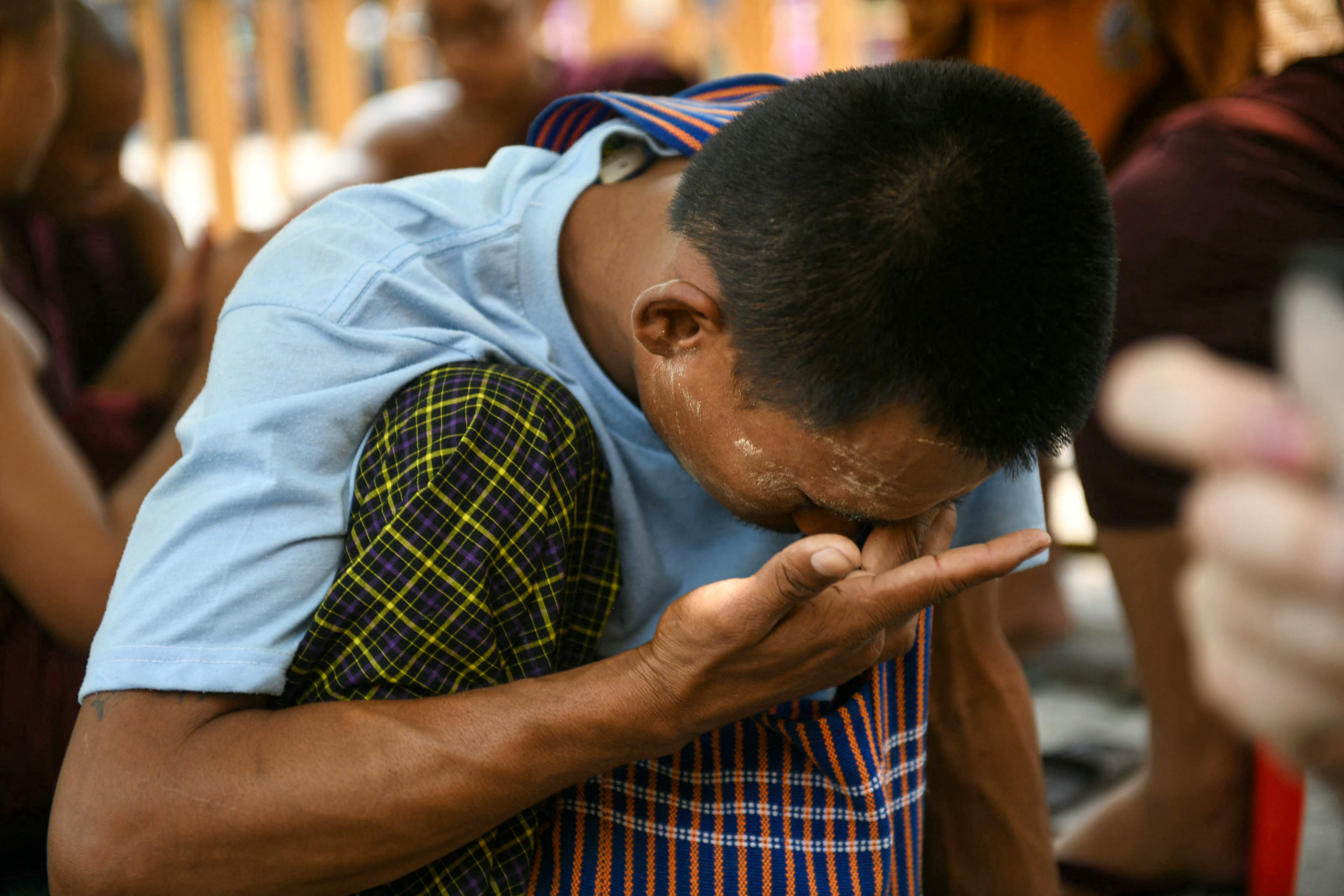 A man waits near a damaged temple in Mandalay during search and rescue operations