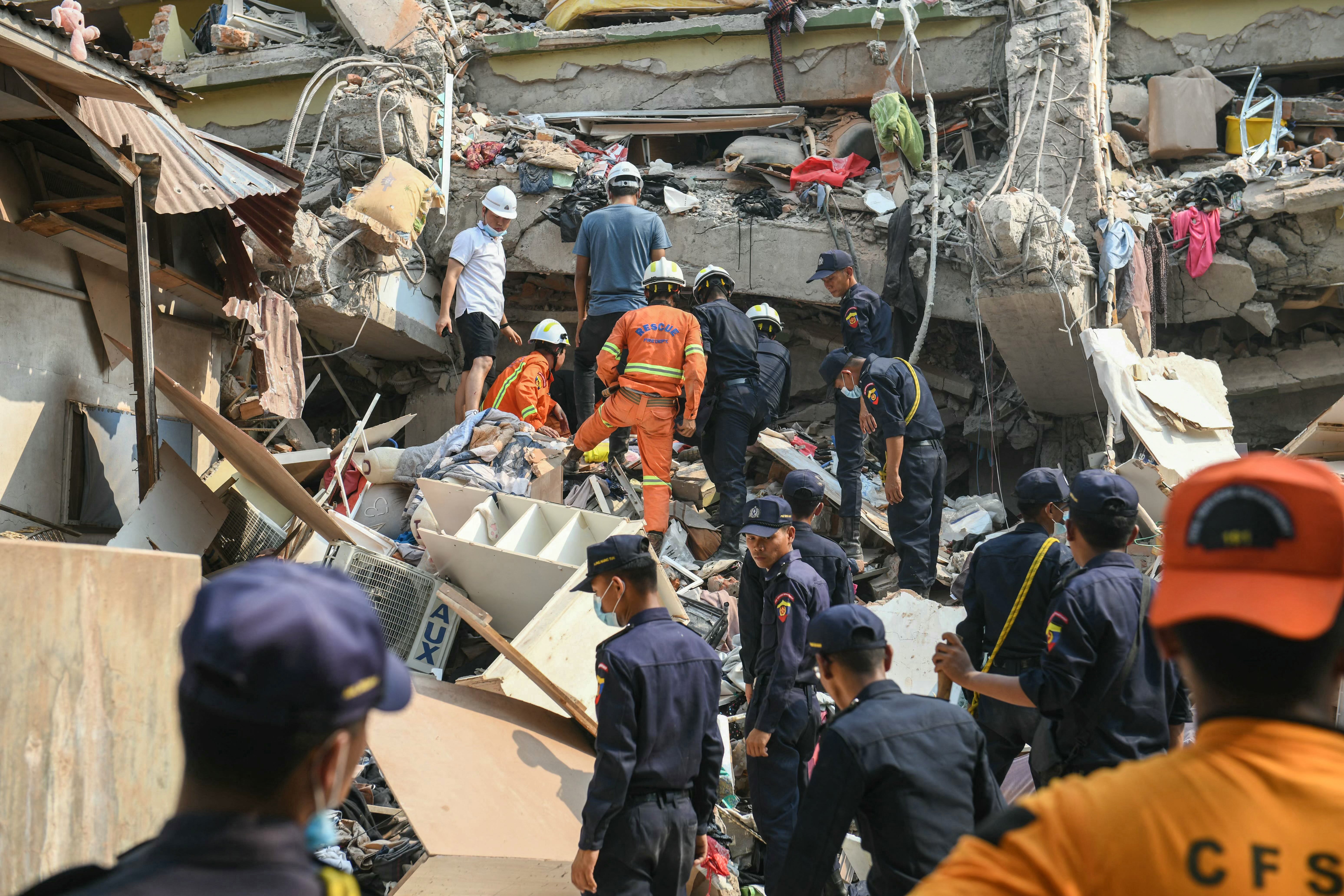 Rescue teams work to save people trapped under the rubble of a building in Mandalay, Myanmar